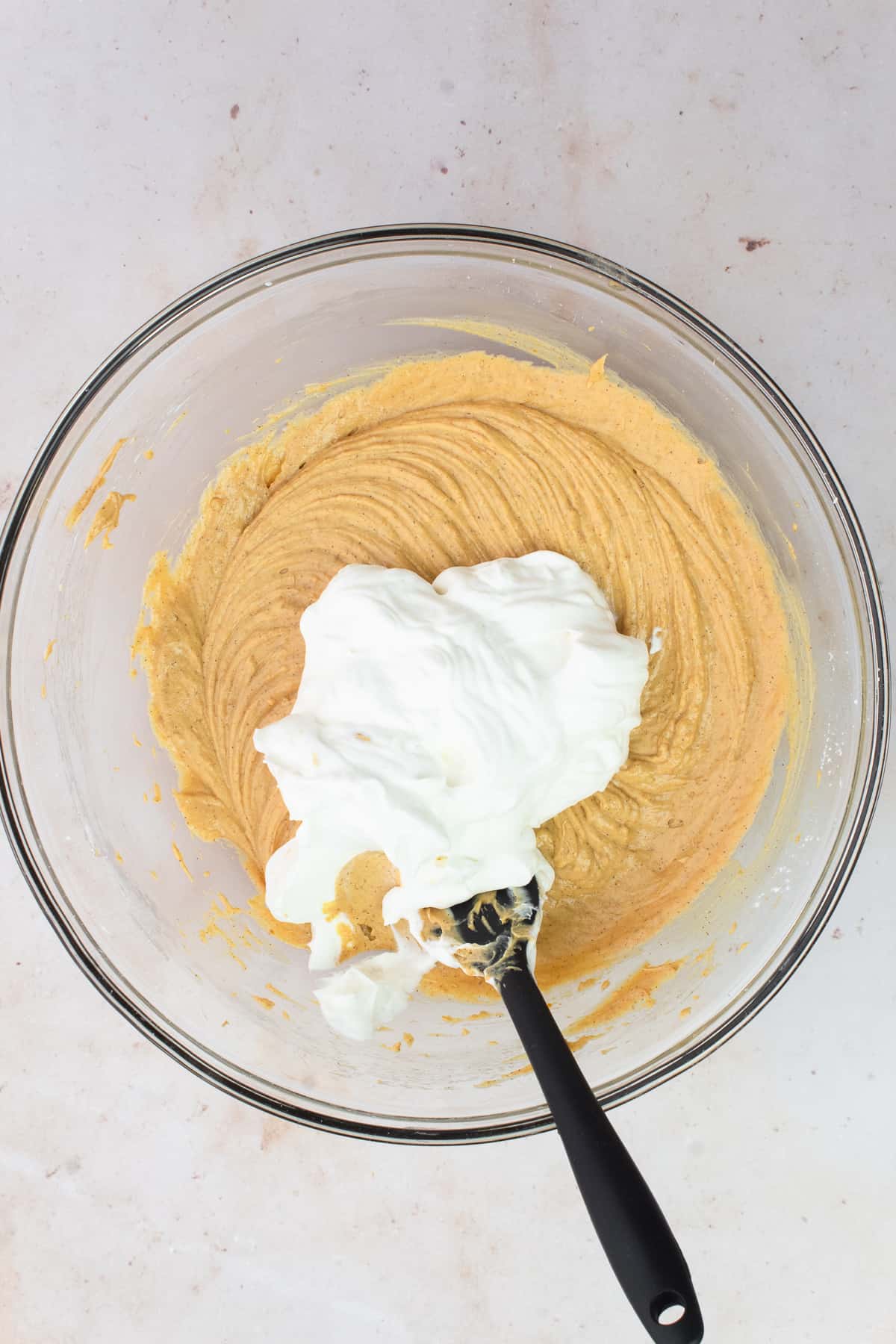 Whipped cream is added to the bowl of pumpkin biscoff cheesecake filling