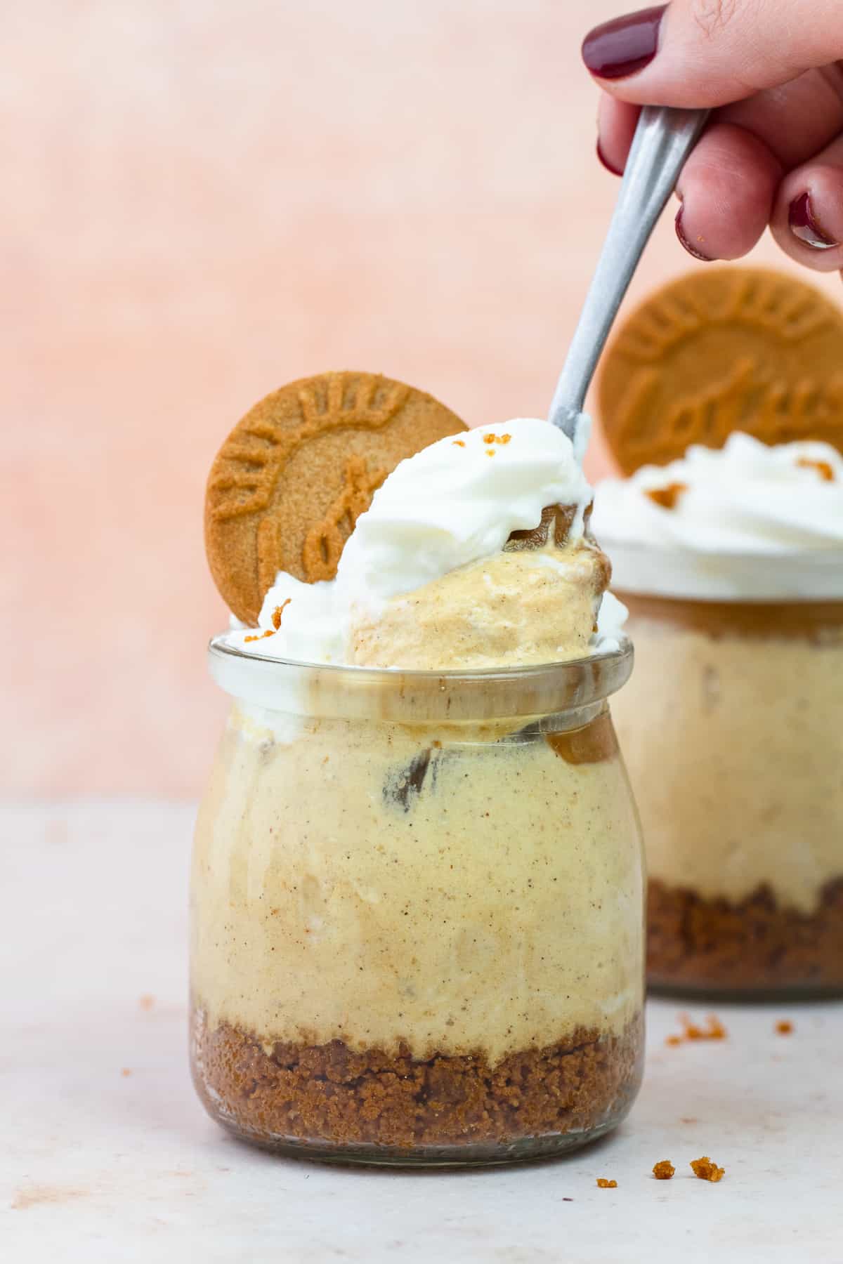 A hand scooping out a spoon of pumpkin Biscoff cheesecake