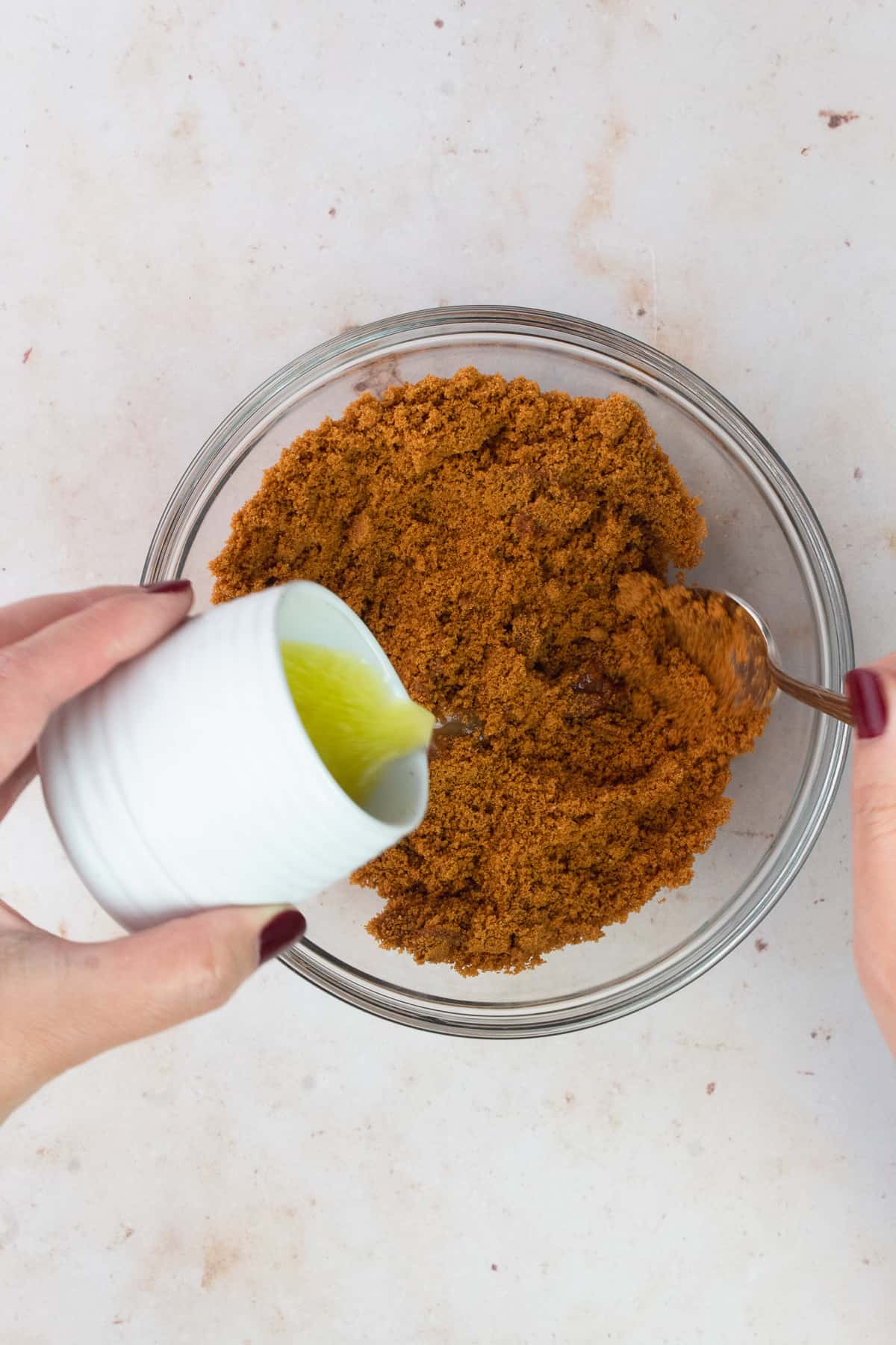 Butter is pouring into a small bowl of cookie crumbs