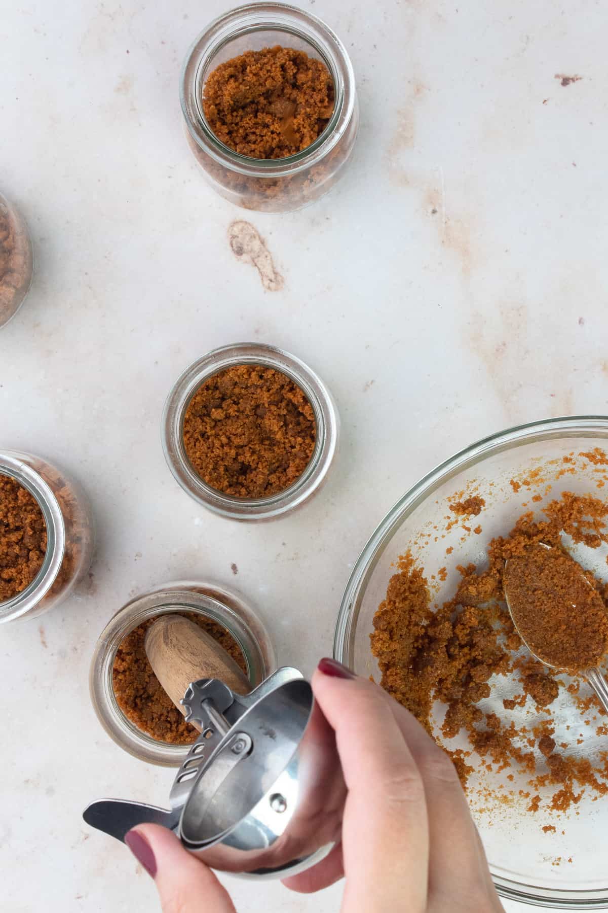 Pressing cookie crumbs into little jars