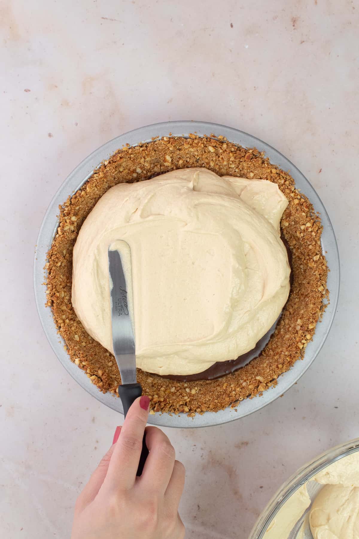 Spatula spreading Peanut Butter filling into pie