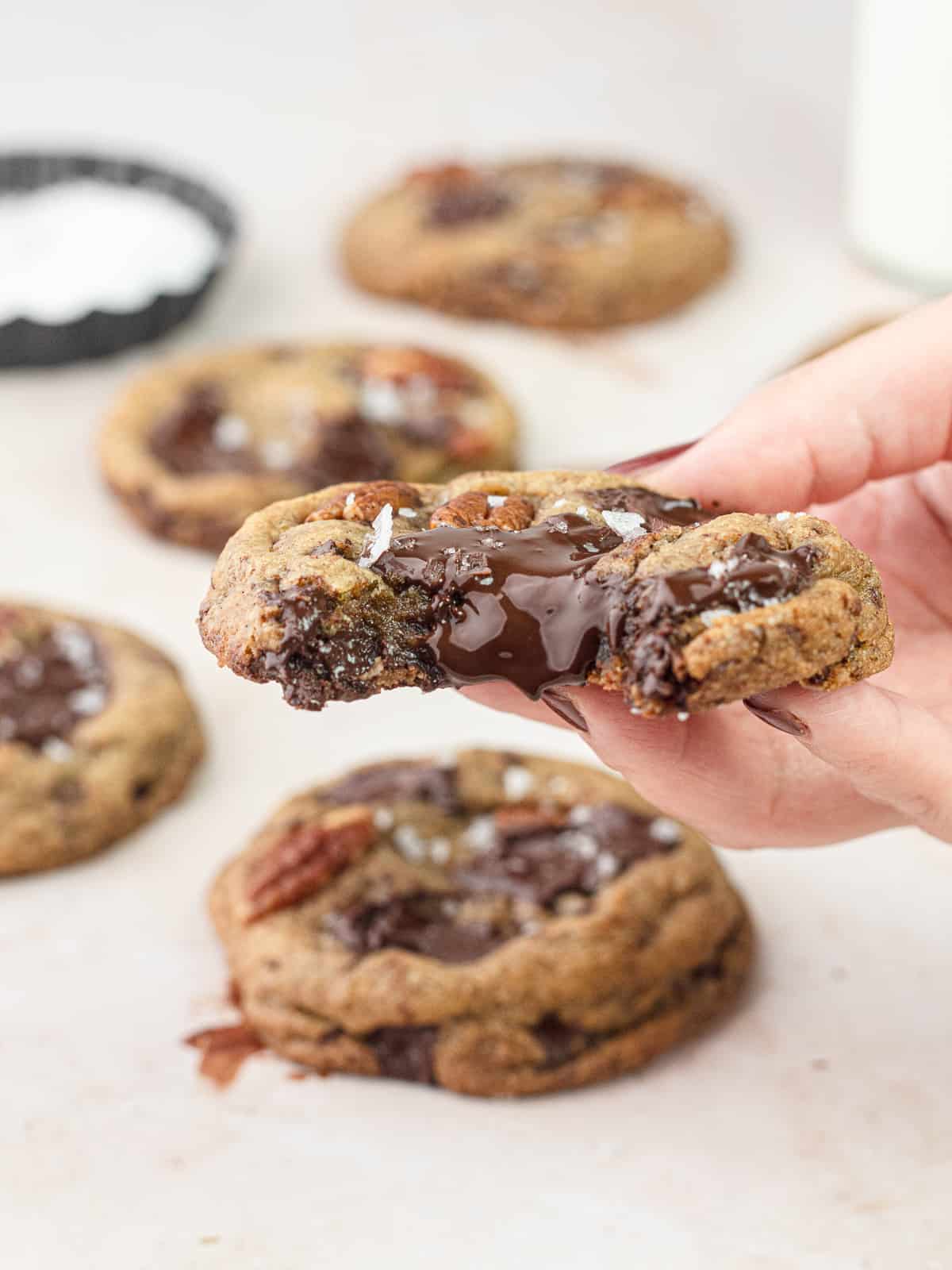 Hand holding a bourbon pecan chocolate chunk cookie