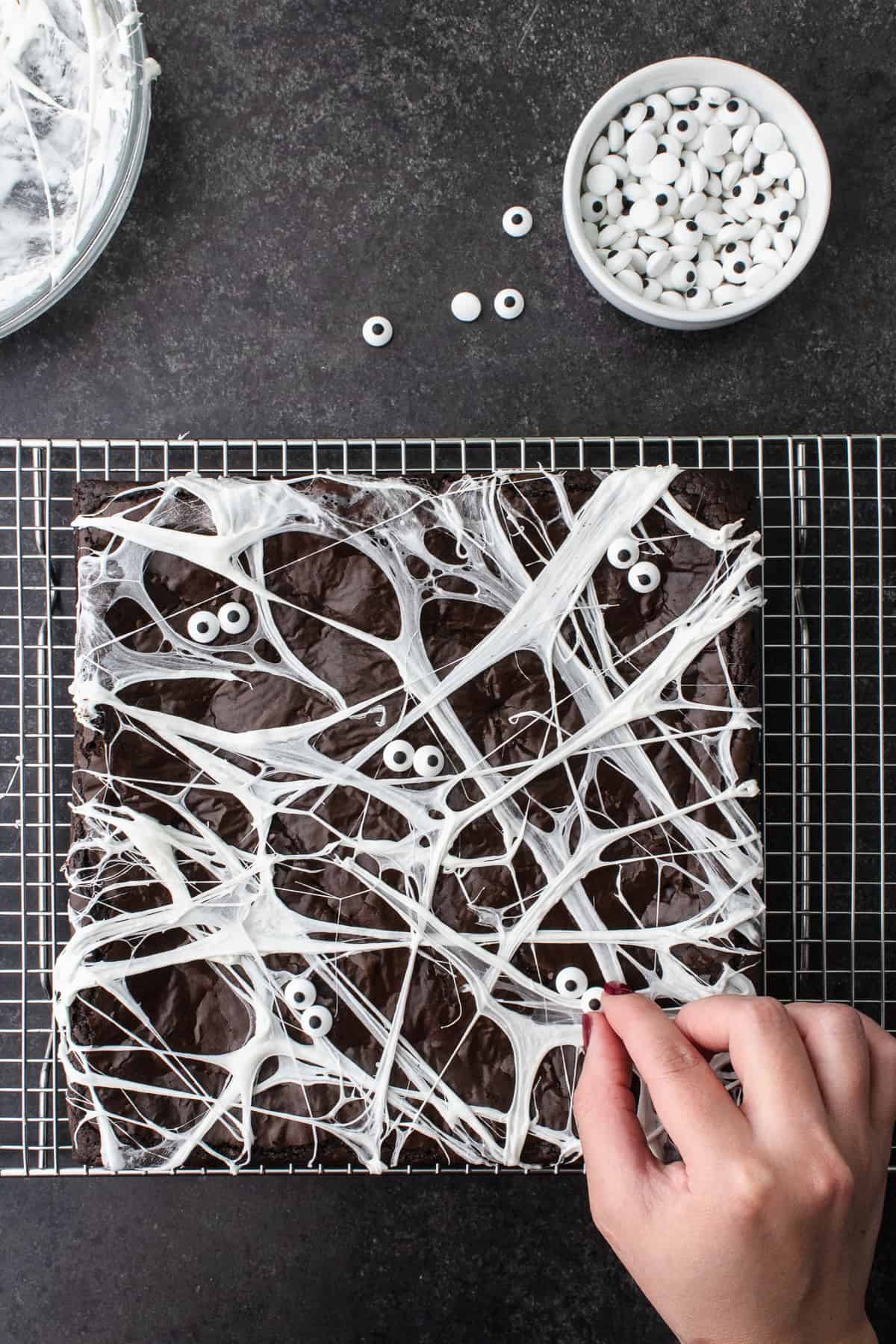 Adding edible eyeballs to marshmallow covered brownies