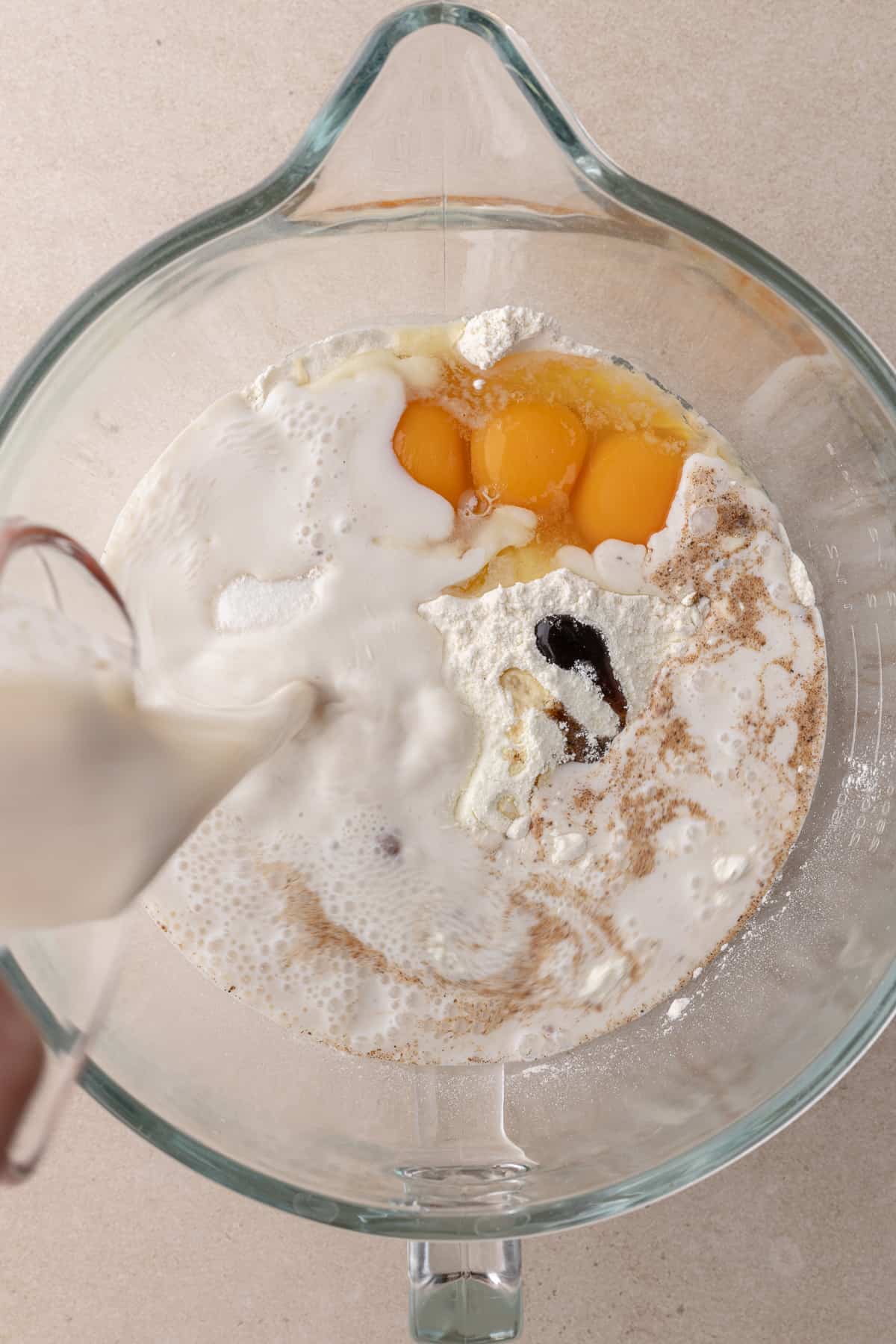 Bloomed yeast is added to a large mixing bowl with bread flour, sugar, milk powder, nutmeg, salt, vanilla, egg, yolk, melted butter and rum