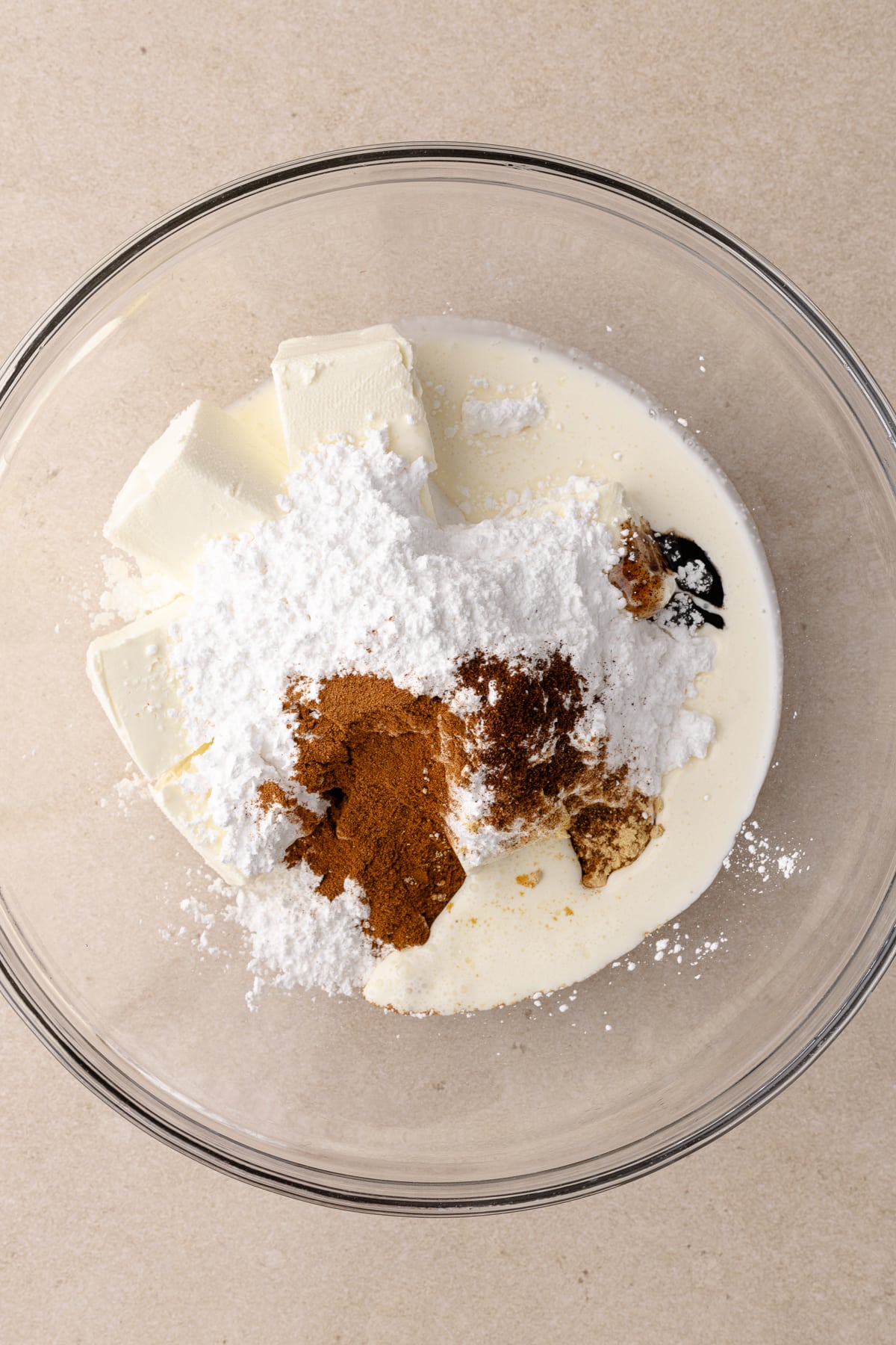 Cream cheese, heavy cream, spices, vanilla and powdered sugar are in a medium bowl