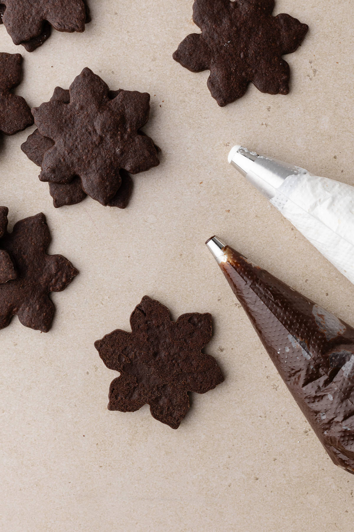 Bottom linzer cookies with a piping bag of chocolate ganache and marshmallow fluff