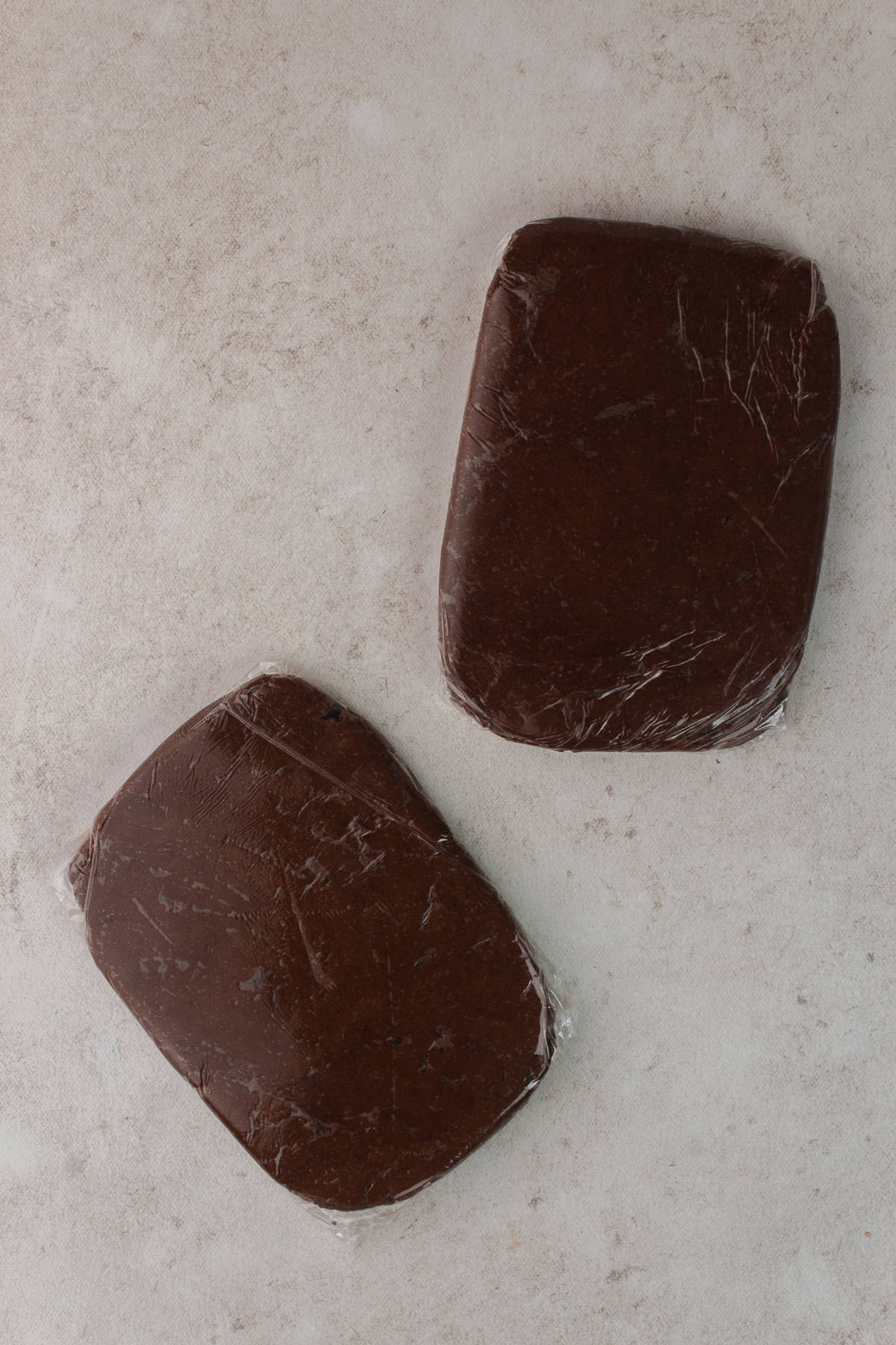 Dough divided into two squares and wrapped in plastic wrap