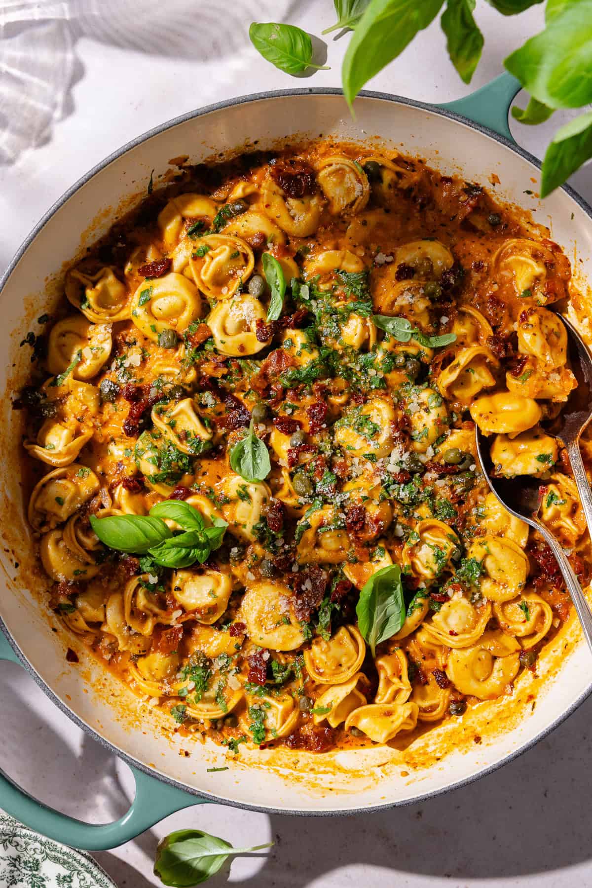 Sun-dried tomato pasta garnished with fresh basil in a large braiser pot.