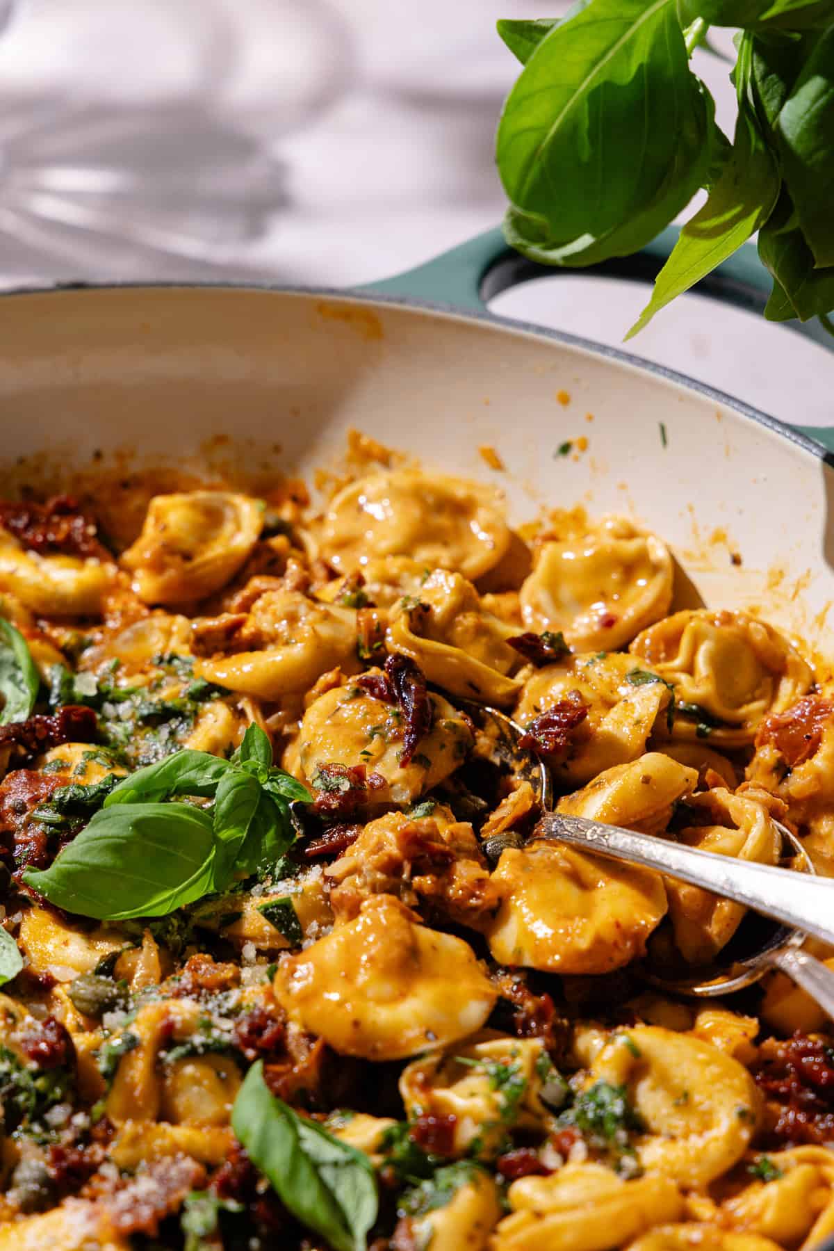 Close up of Sun-dried tomato pasta garnished with fresh basil in a large braiser pot.