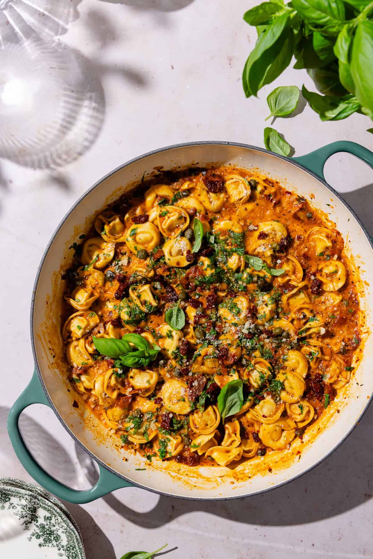 Sun-dried tomato pasta garnished with fresh basil in a large braiser pot.