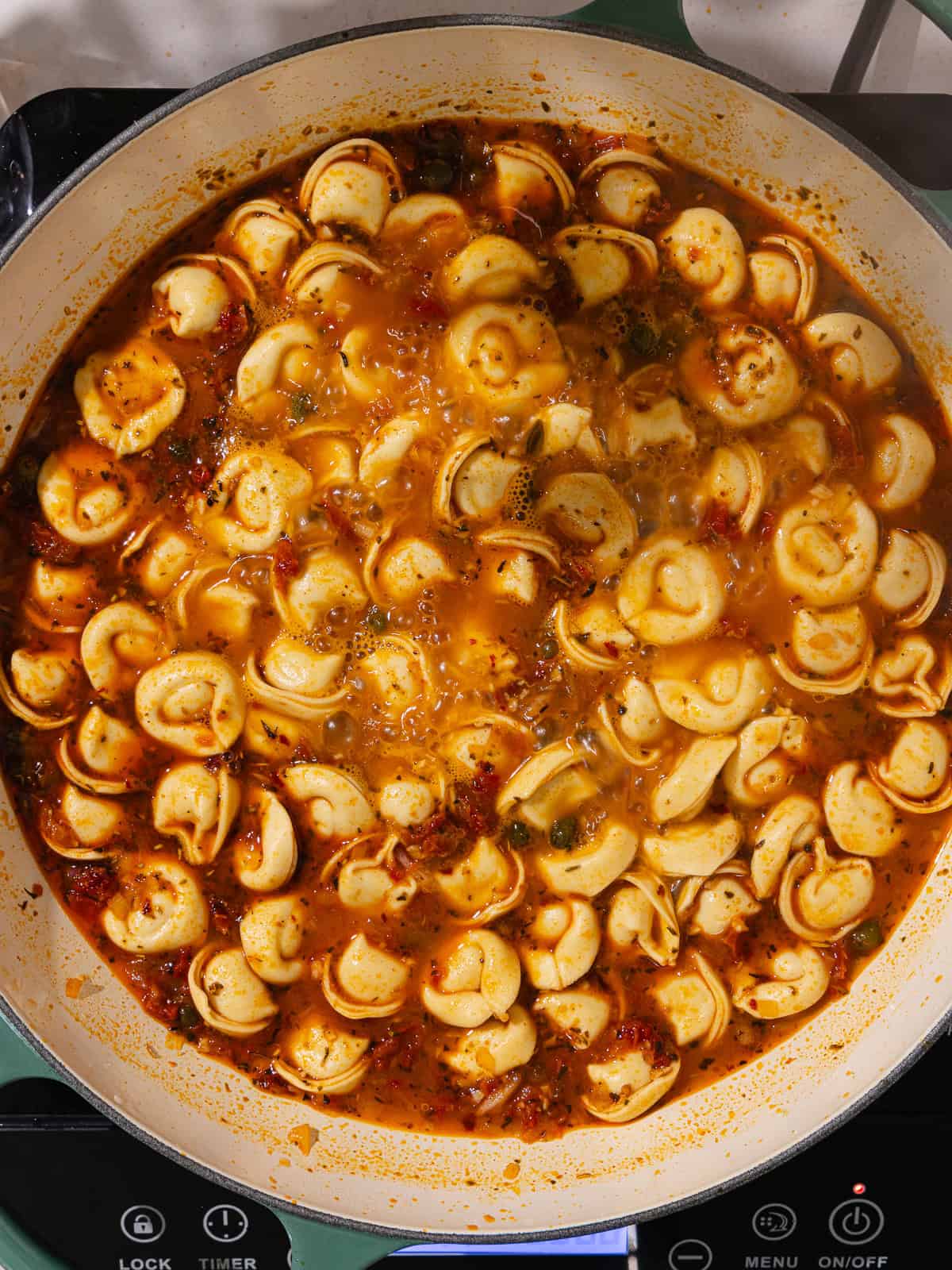 Tortellini is added to the pan.