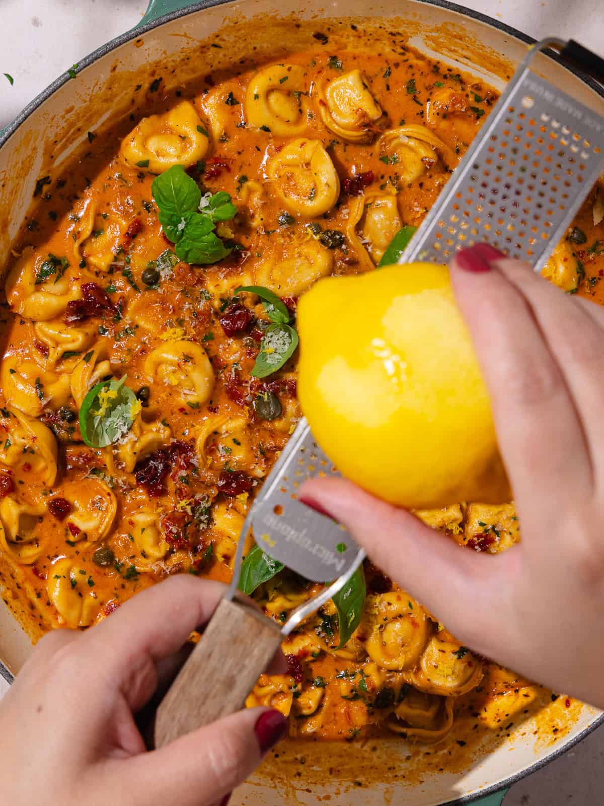 Lemon zest is added to cooked sun-dried tomato pasta.