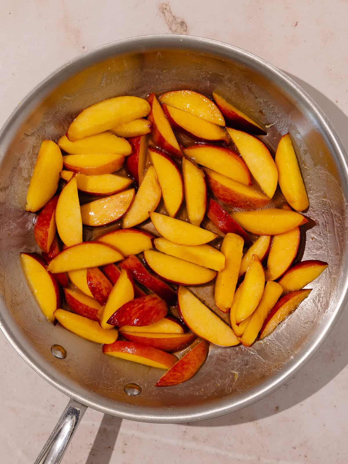 Peaches are sauteed in a pan with butter, sugar, lemon zest, lemon juice and vanilla.