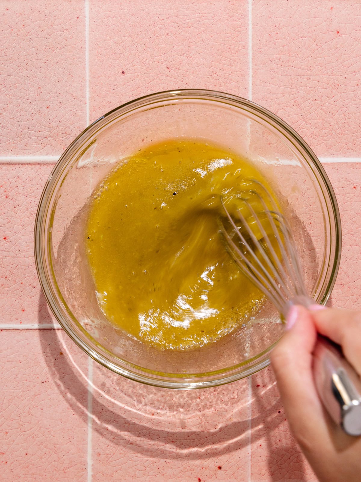 A hand whisks the vinaigrette.