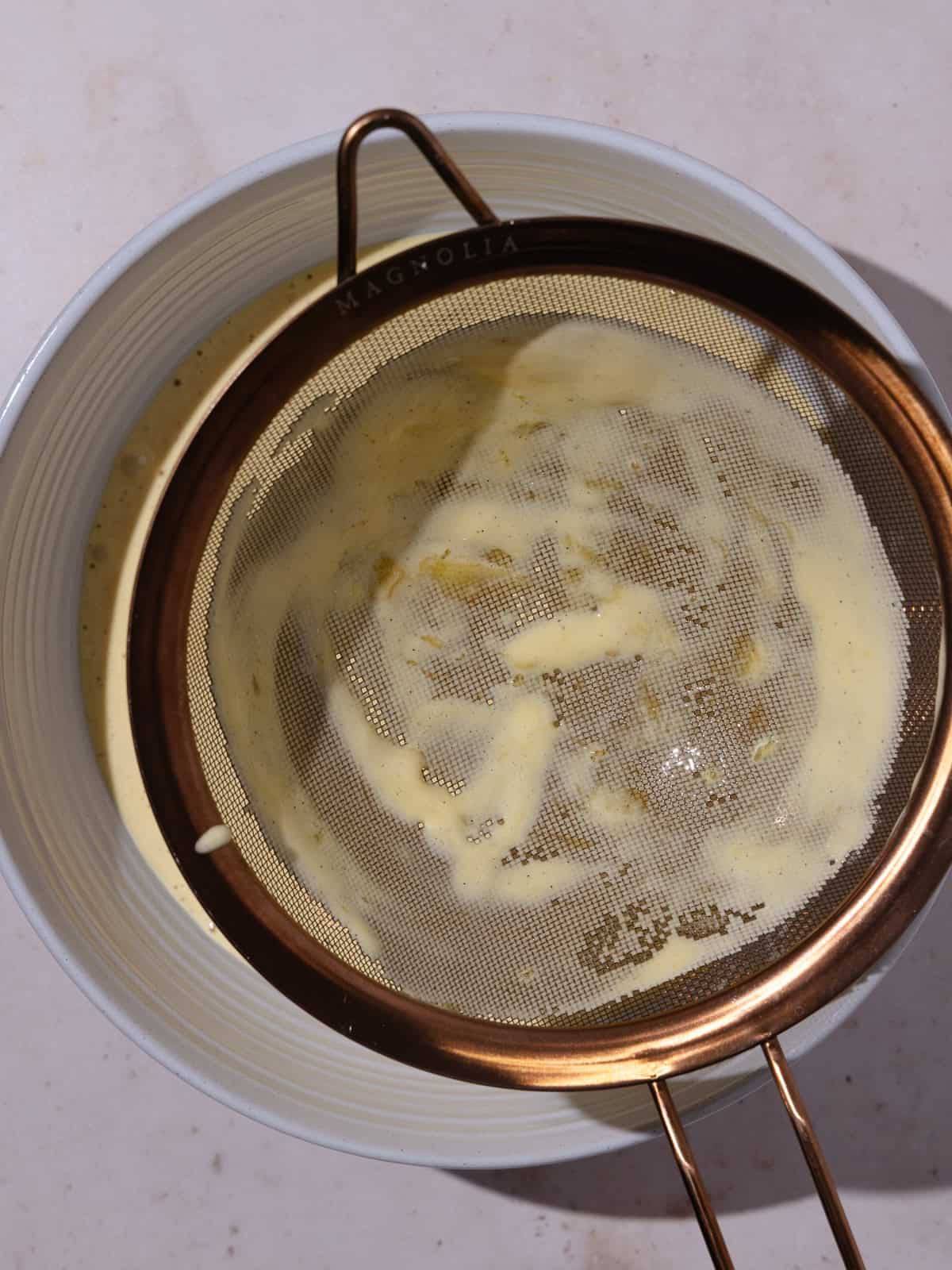 The yolk/sweetened condensed milk mixture is strained into another bowl.