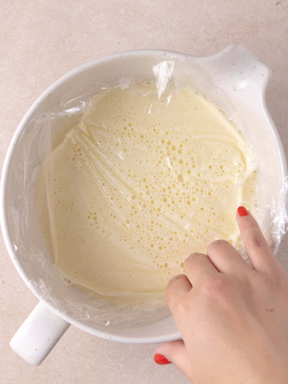 Placing cling film on top of the custard to prevent a skin from forming.