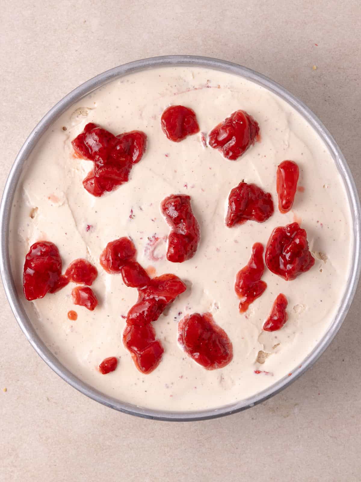 A layer of strawberry jam is added on top of the ice cream.