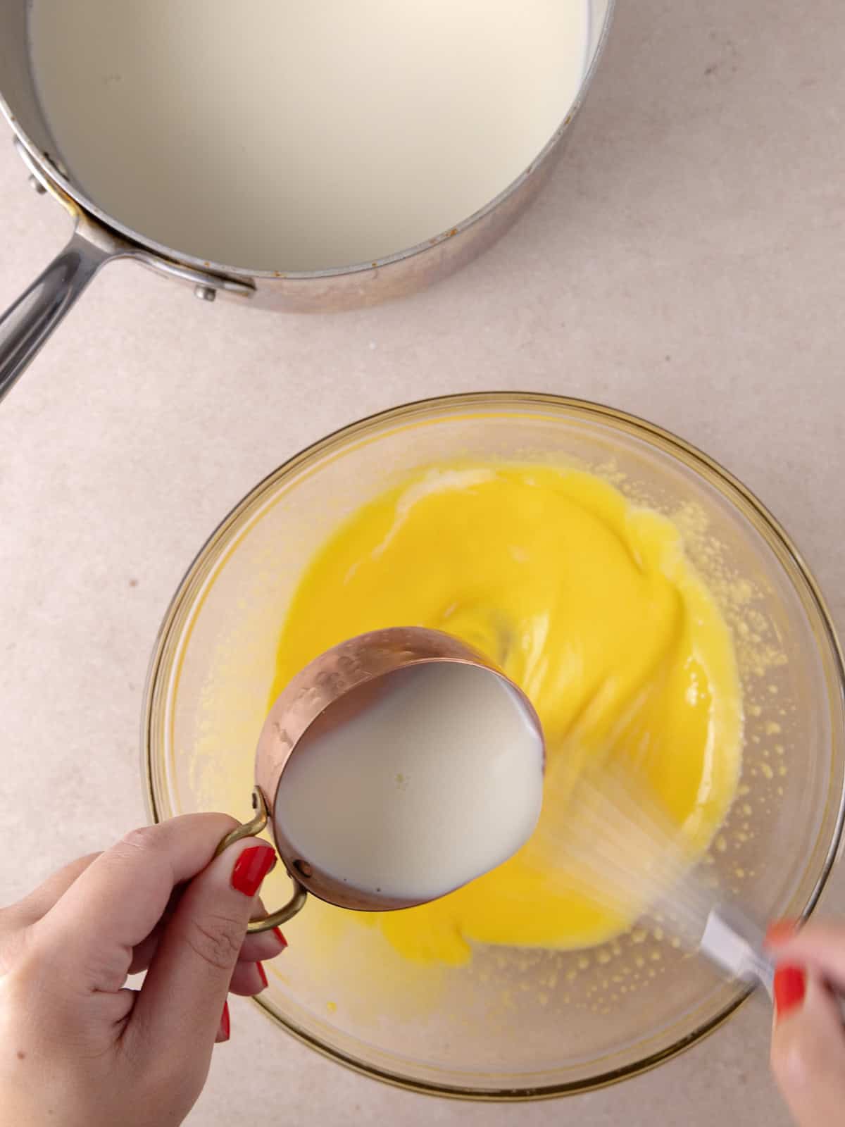 Heavy cream/milk mixture is added slowly into the whipped yolk mixture.