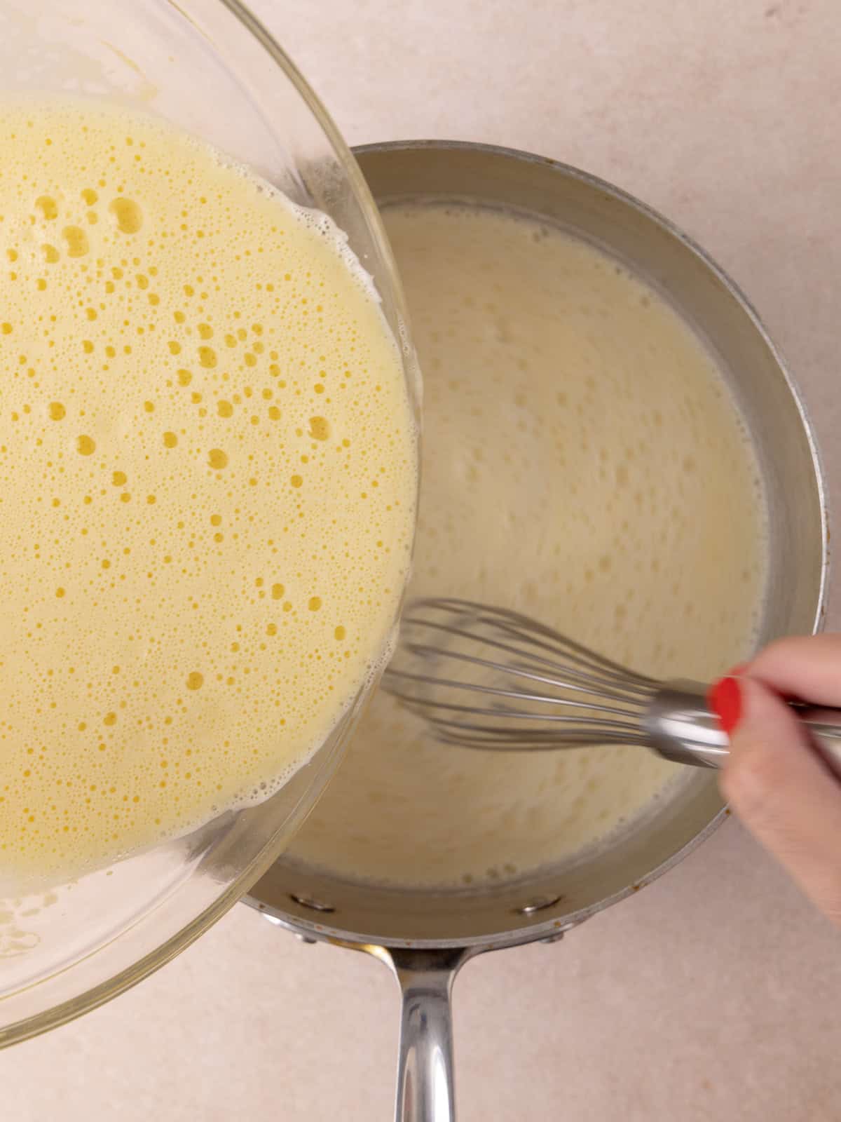 Tempered yolk sugar mixture is added back into the pot with cream/milk mixture.