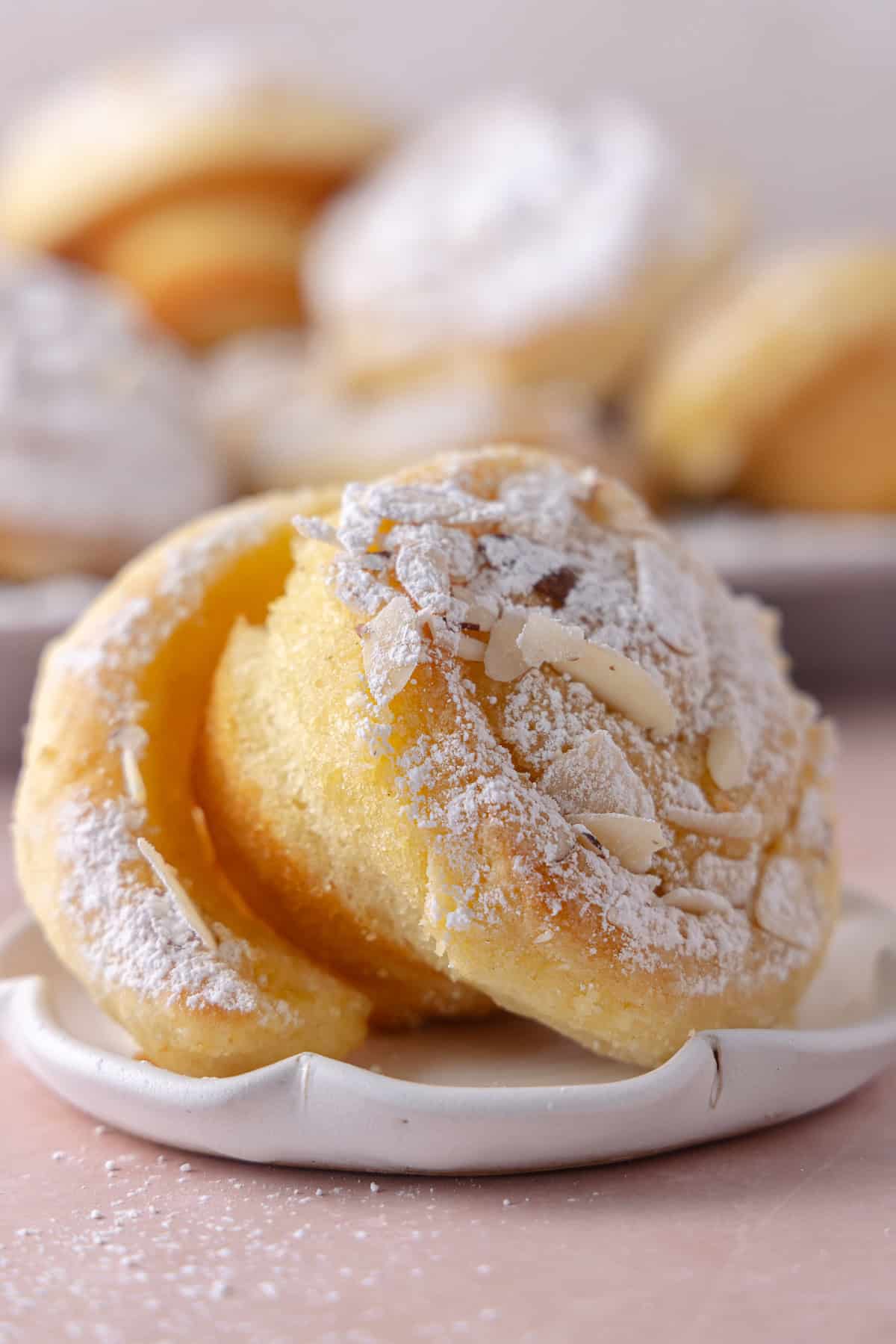 Close up of an almond croissant roll sitting on a plate.