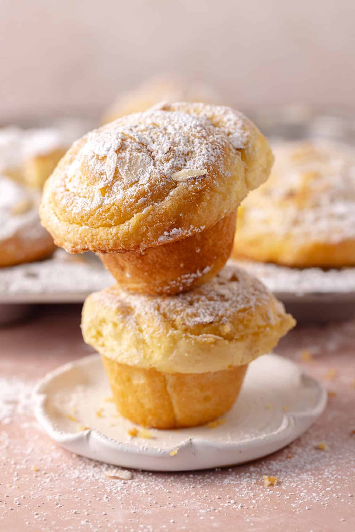 Two almond croissant rolls stacked on a plate.