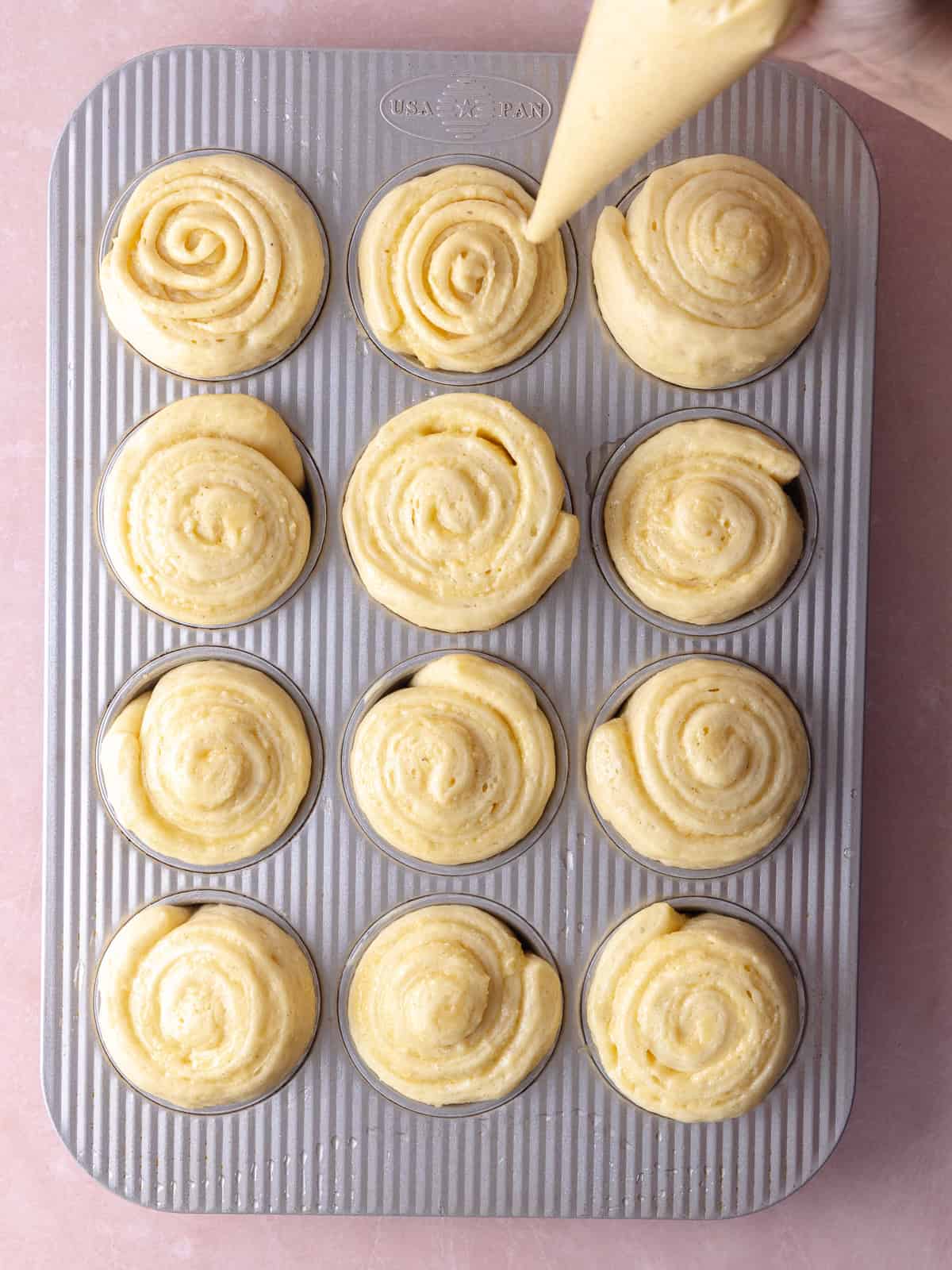 After rolls have risen, a piping of more almond frangipane is added on the tops.