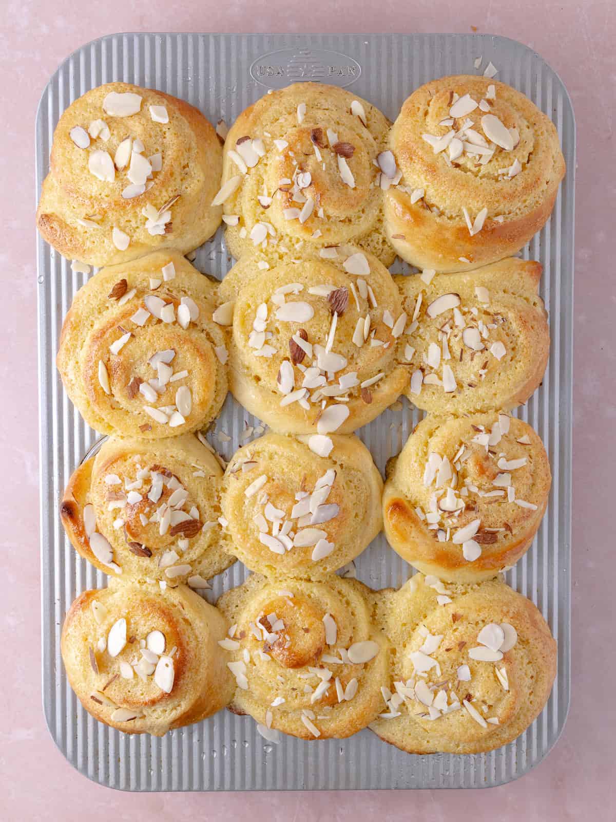 Syrup and slice almonds are added to the top of watch almond croissant rolls.