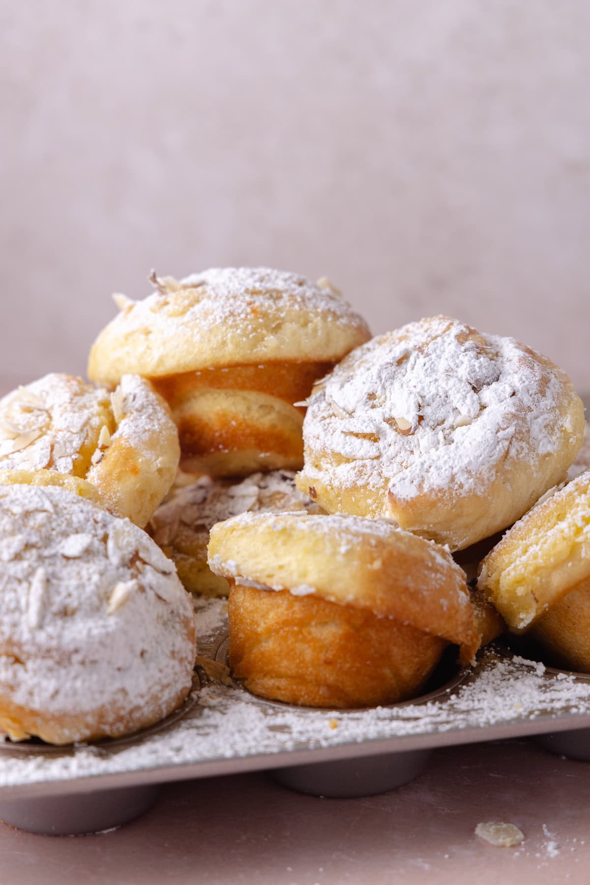 A pile of almond croissant buns in a muffin tin.