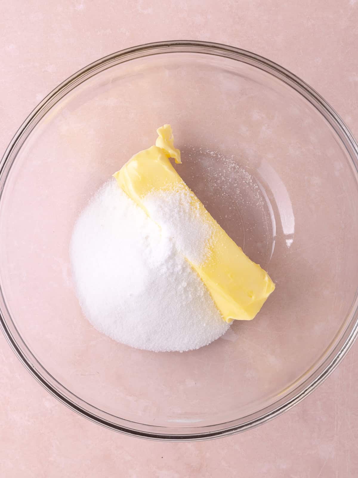 White sugar and unsalted butter are in a glass mixing bowl