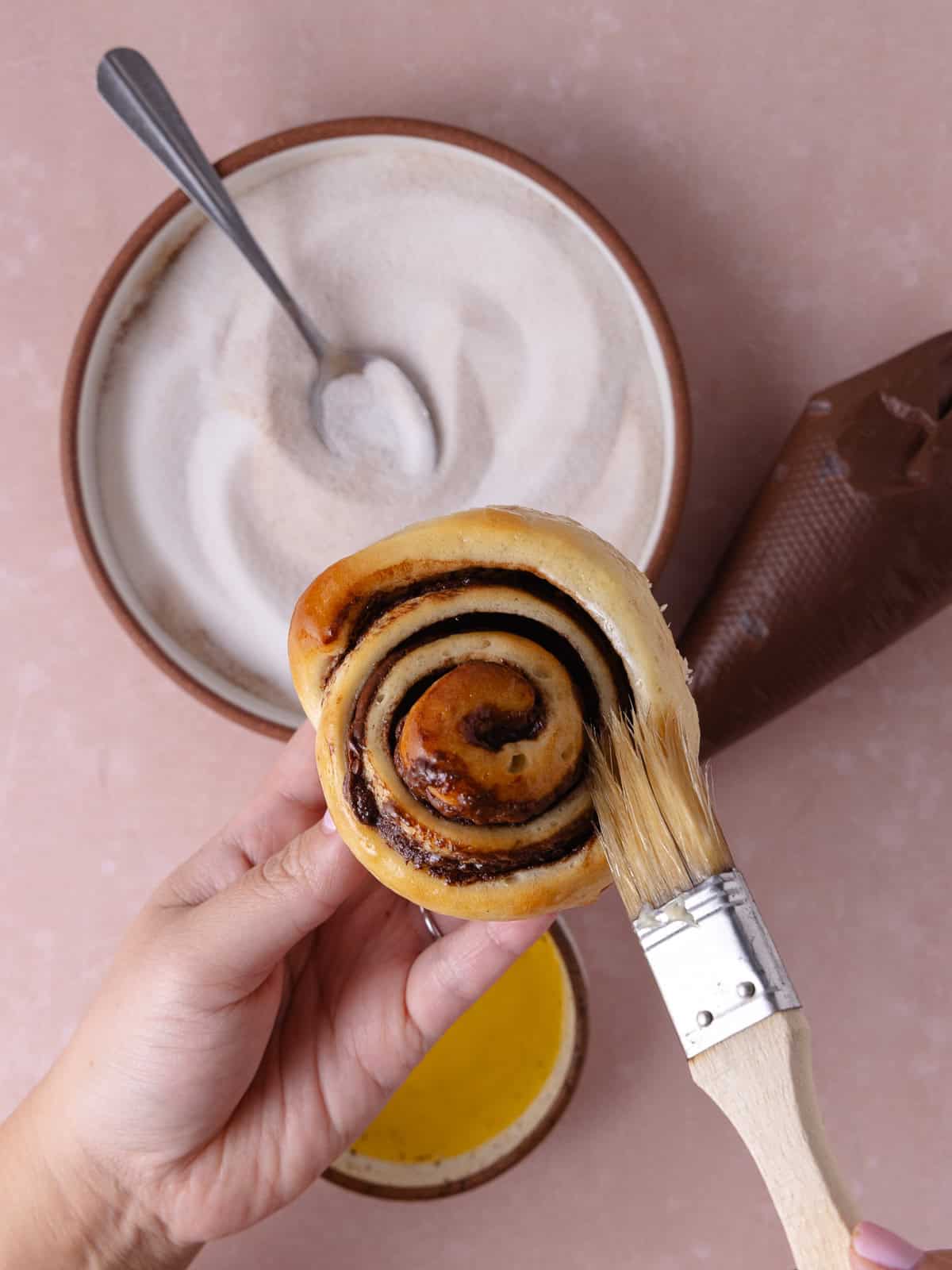 A Nutella cinnamon roll gets lightly brushed with melted butter.