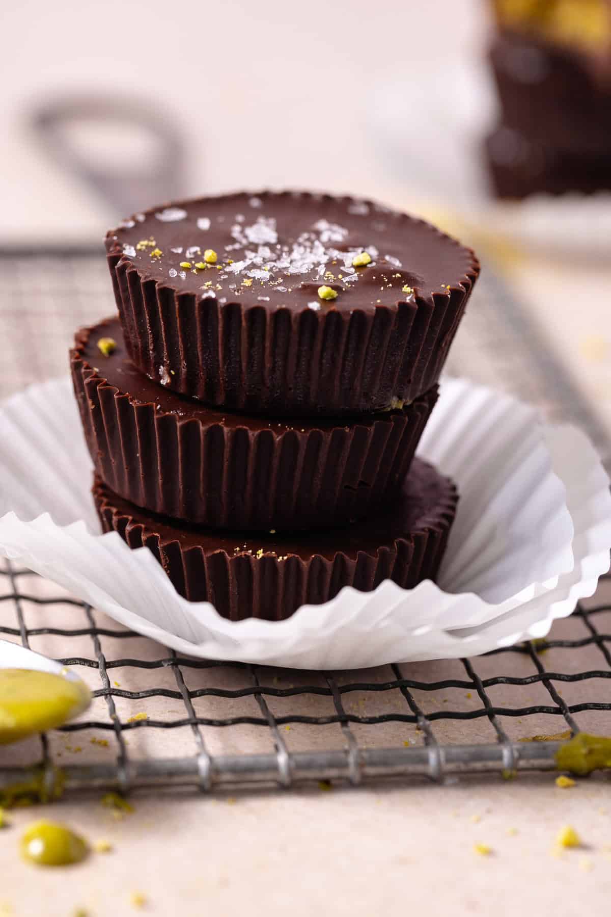 A stack of of three pistachio butter cup on a rack.