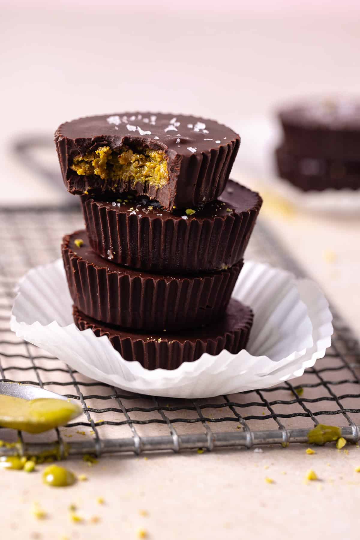 A stack of pistachio butter chocolate cups on a wire rack.