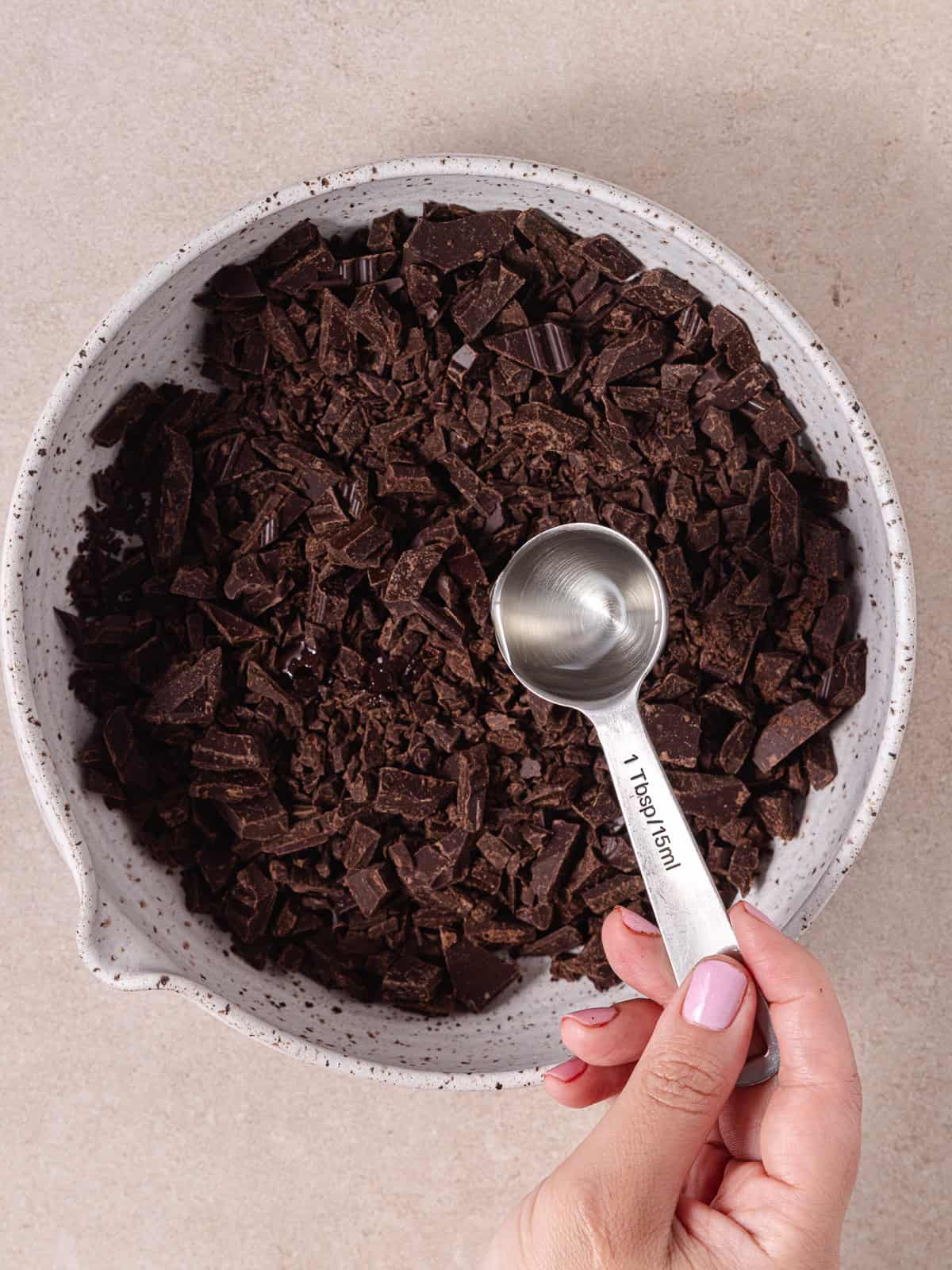 Chopped chocolate and coconut oil are added to a mixing bowl.