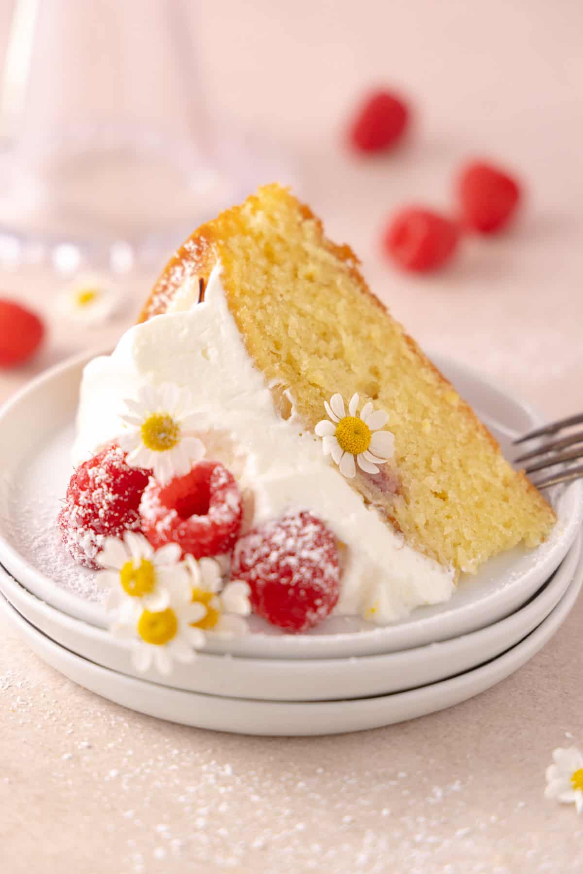 Close up of a slice of raspberry almond cake on a stack of plates.