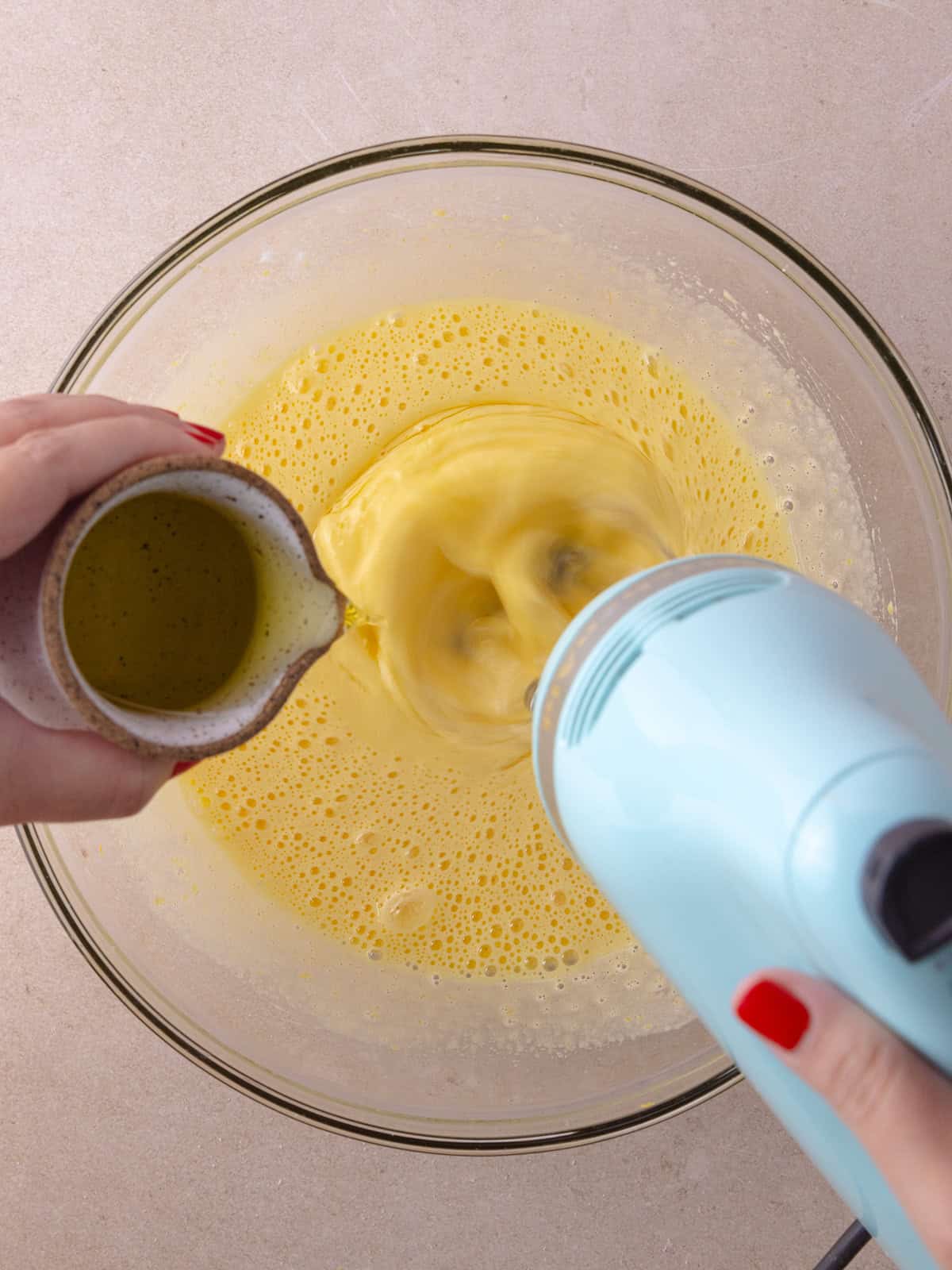 Olive oil is drizzled into the egg and sugar mixture.