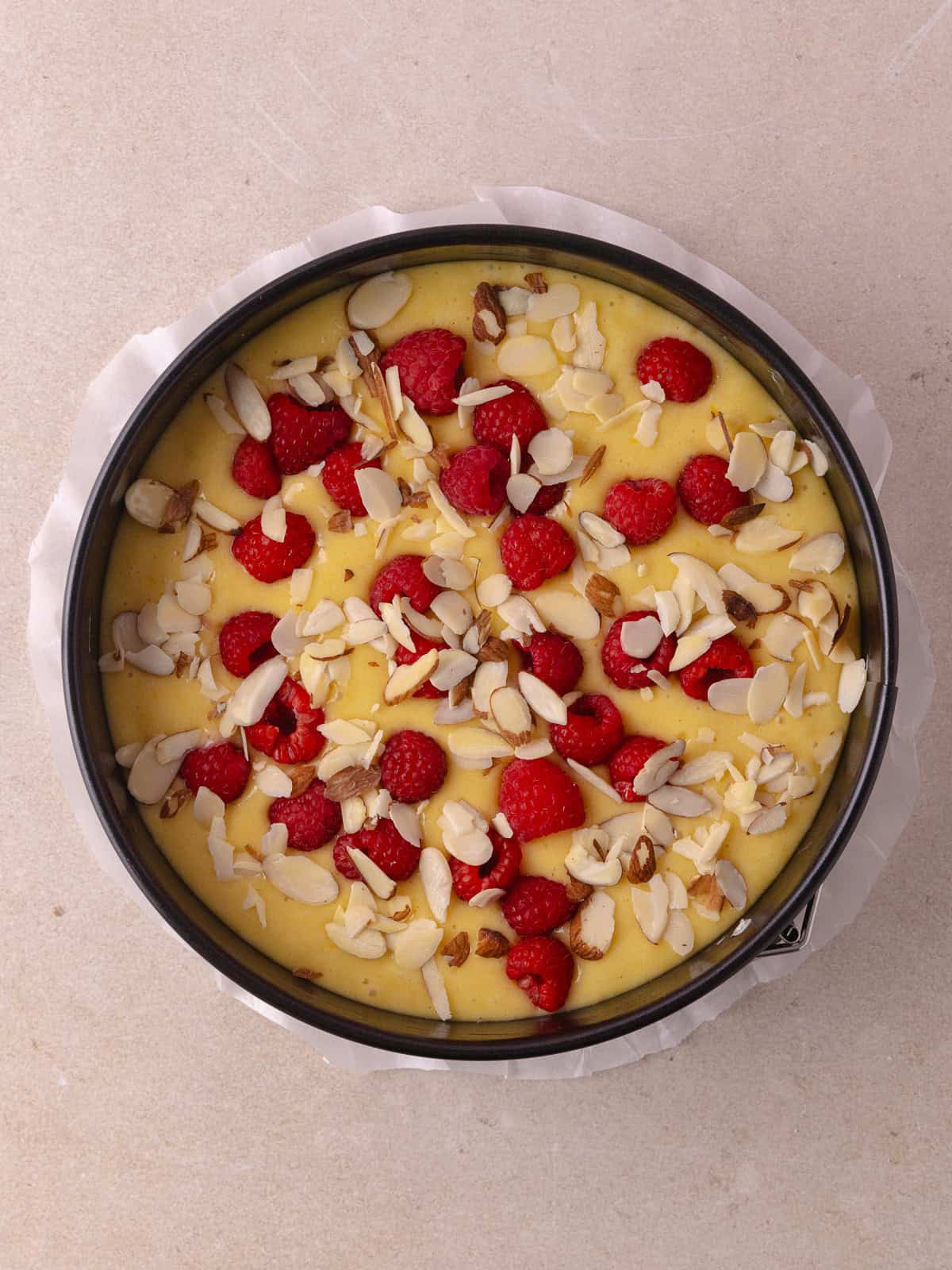 Cake batter is topped with fresh raspberries and sliced almonds.