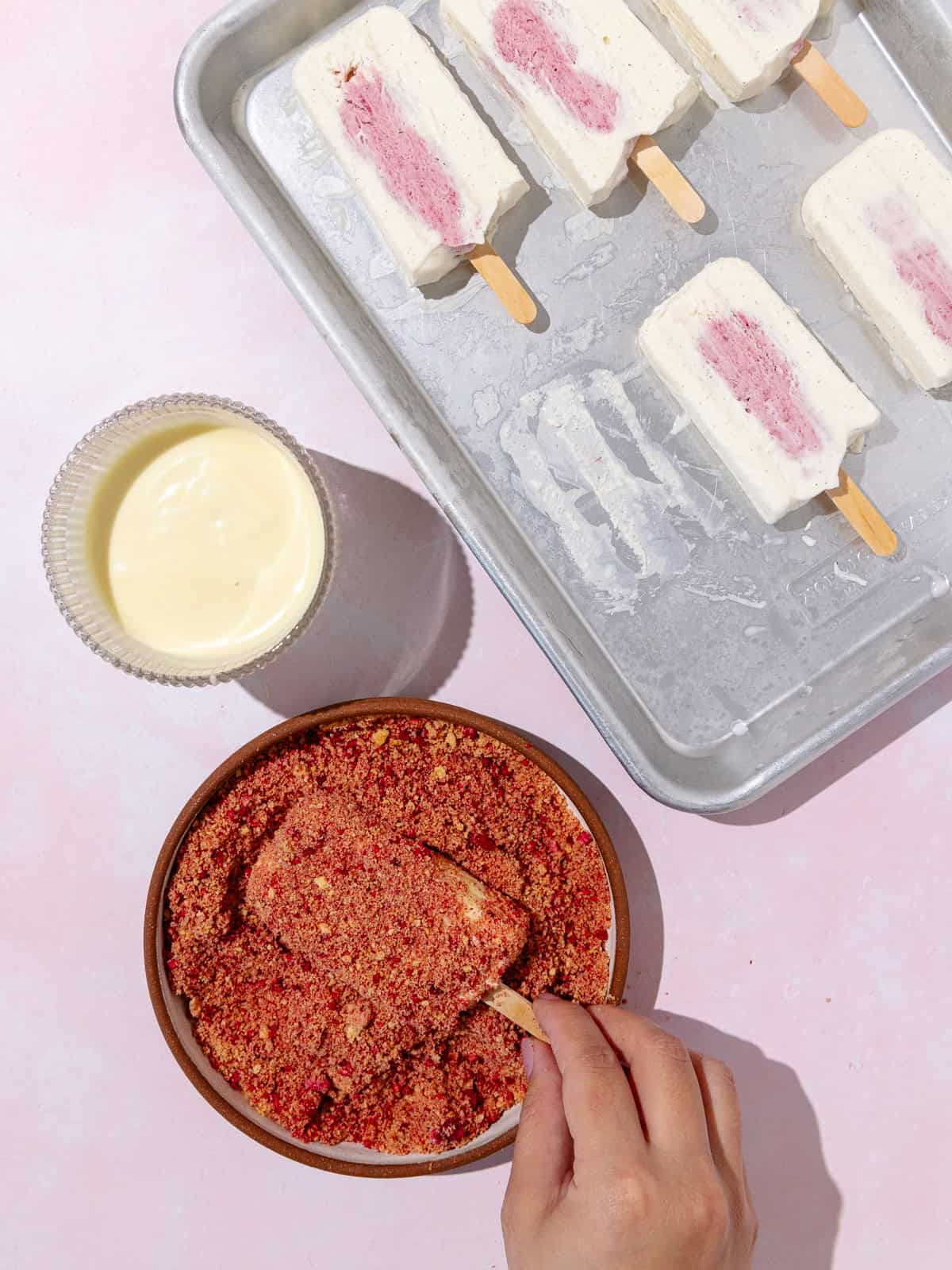 Ice cream dipped in white chocolate is then immediately crumb coated with crusher cookies and raspberry powder.