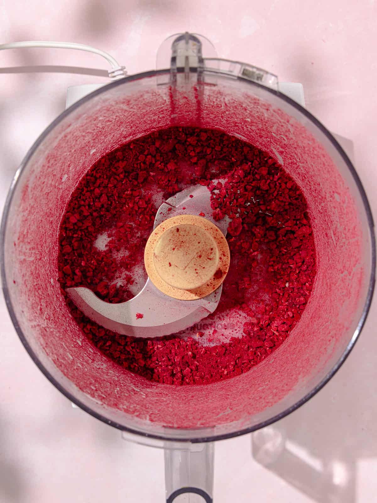 Freeze dried raspberries are pulsed in a food processor.