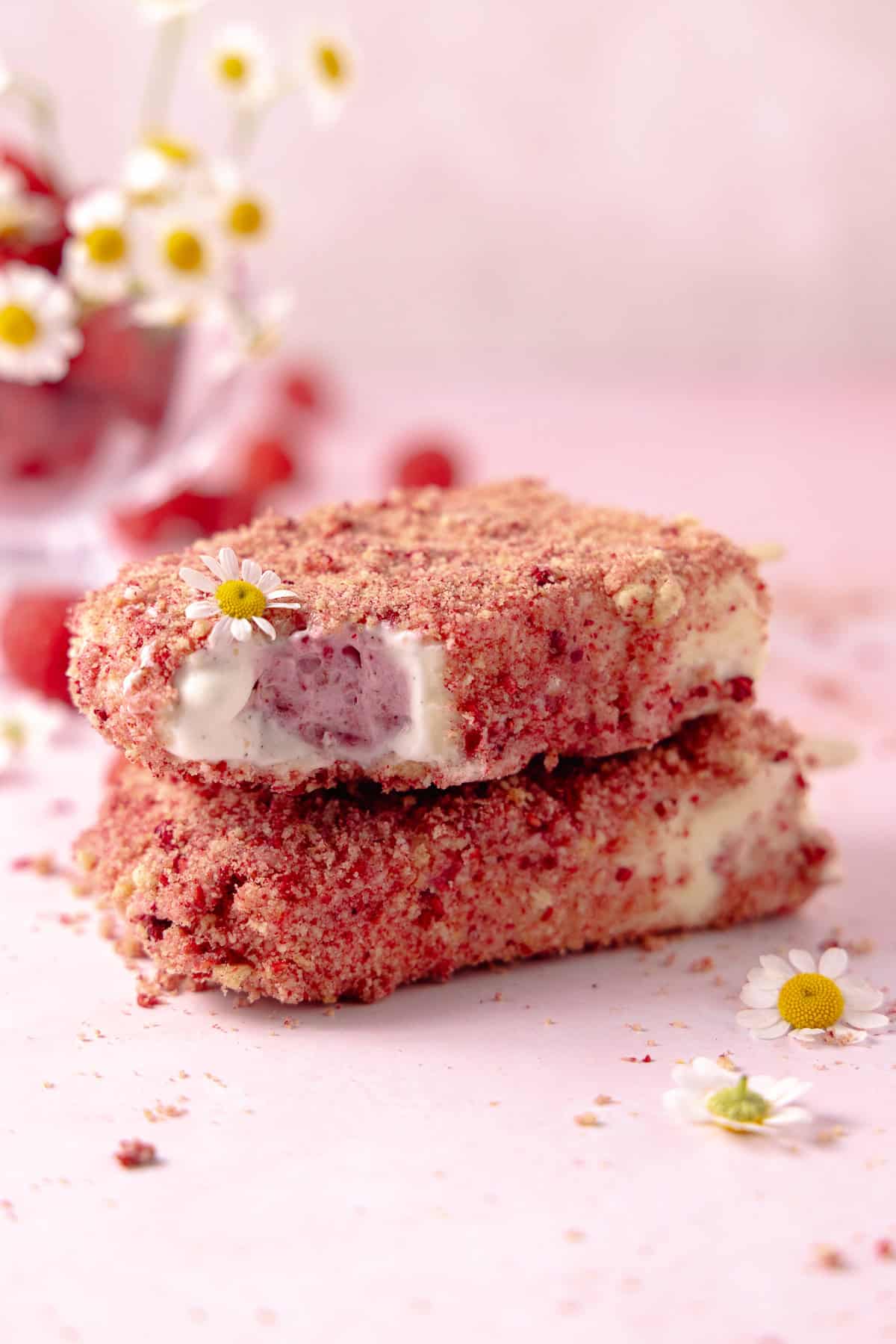 Two Raspberry shortcake ice cream bars stack on top of one another. The top has a bite taken out of it.