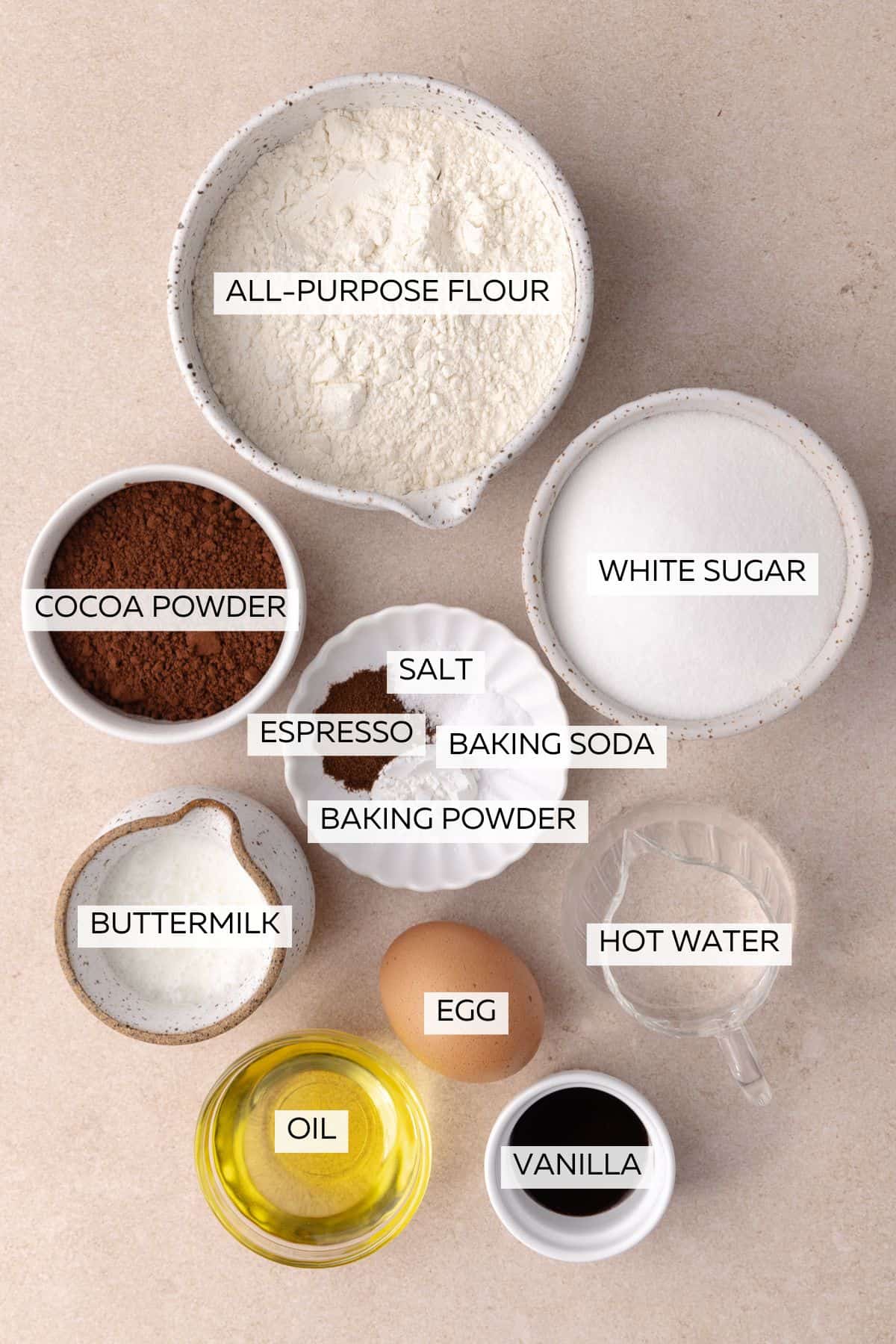 Chocolate cake ingredients which include, flour, white sugar, cocoa powder, baking soda, baking powder, salt, egg, oil, vanilla, buttermilk and hot water.