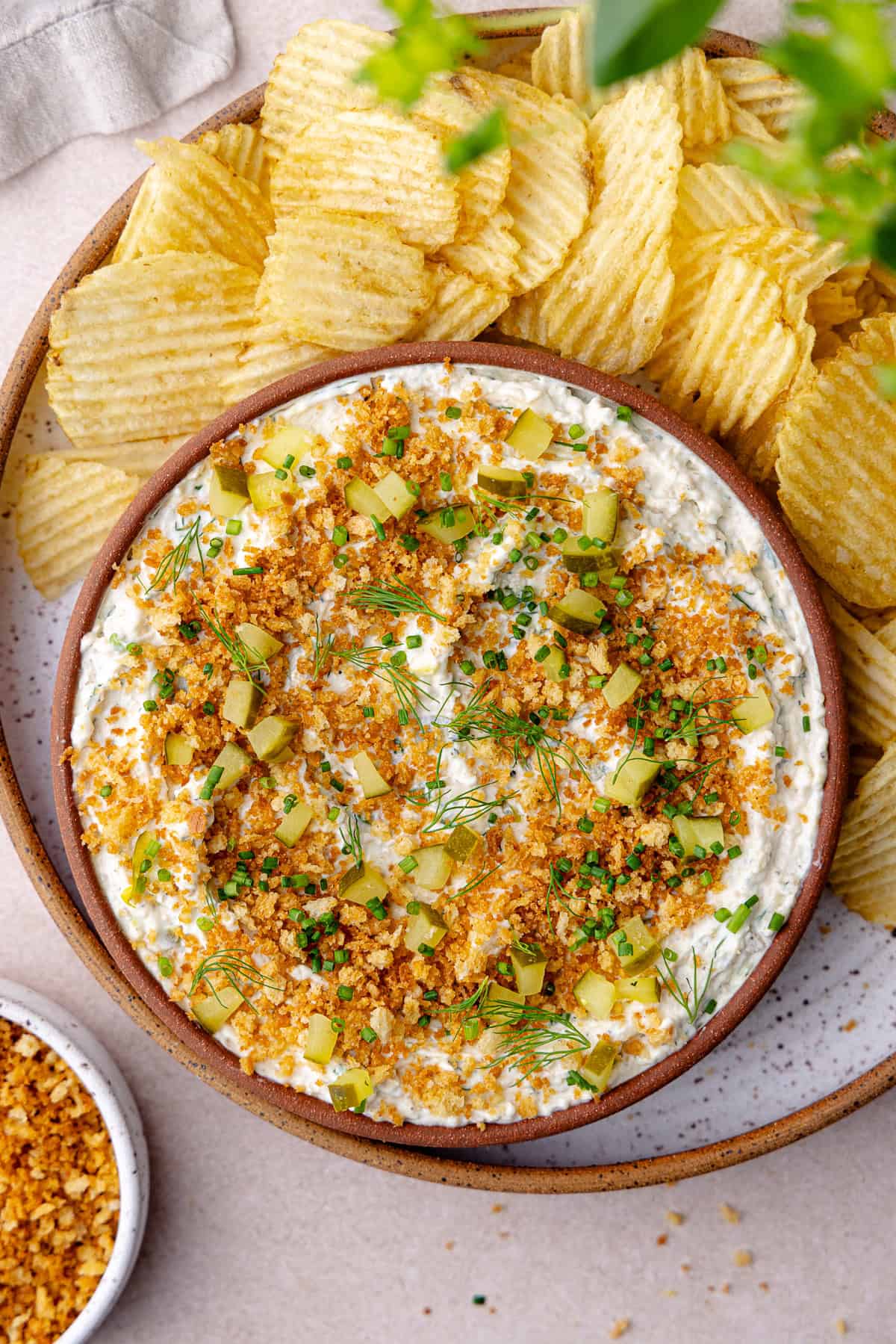 Fried pickle dip in a bowl with wavy potato chips.