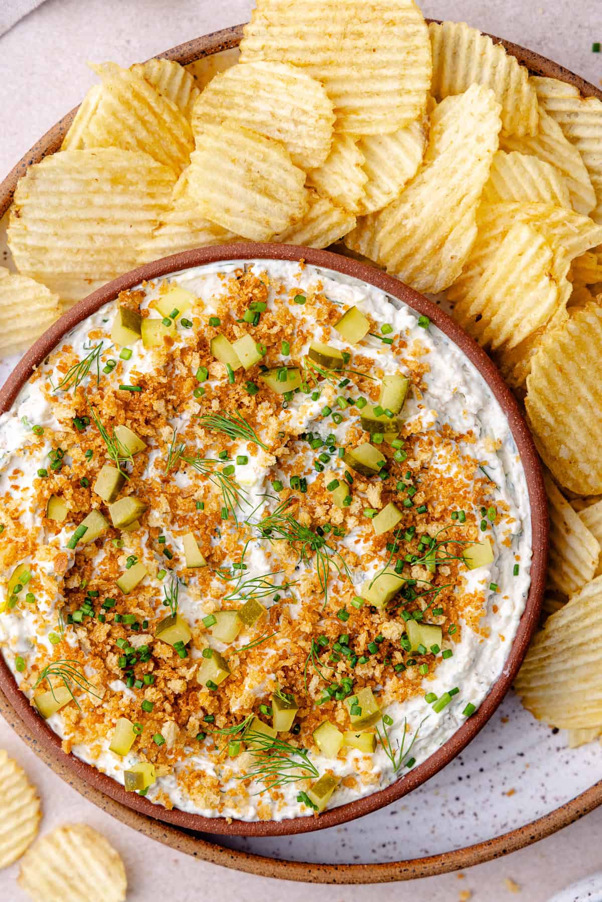 Fried pickle dip in a bowl with wavy potato chips.