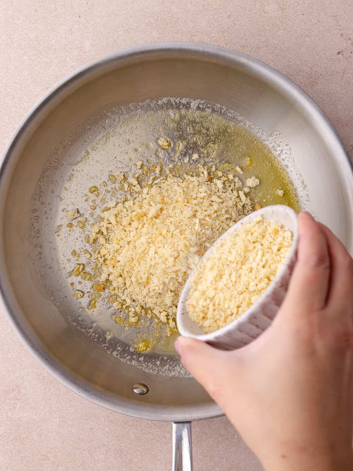 Panko crumbs are added to a pan of melted butter.