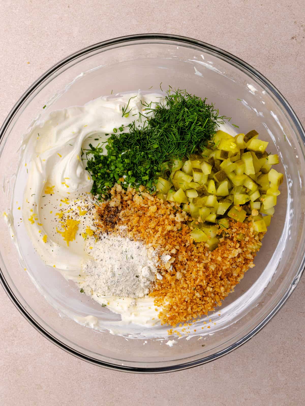 Cream cheese, sour cream, ranch seasoning, black pepper, lemon zest, fresh dill, fresh chives and diced pickles, pickle juice and toasted bread crumbs are in a large mixing bowl.