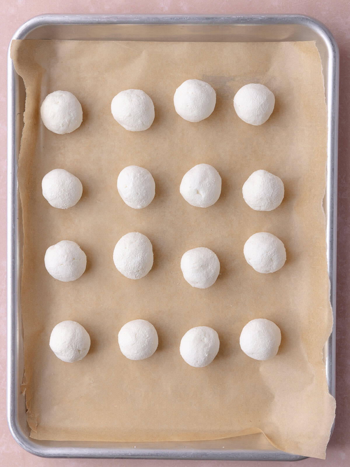 Goat cheese pieces are rolled into balls and placed on a small baking tray.