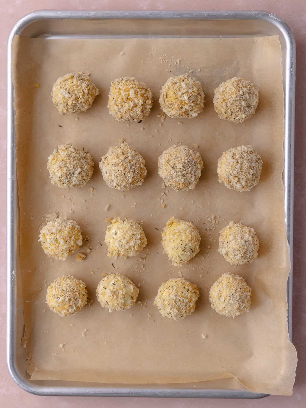 Breaded goat cheese balls are on a small baking tray.