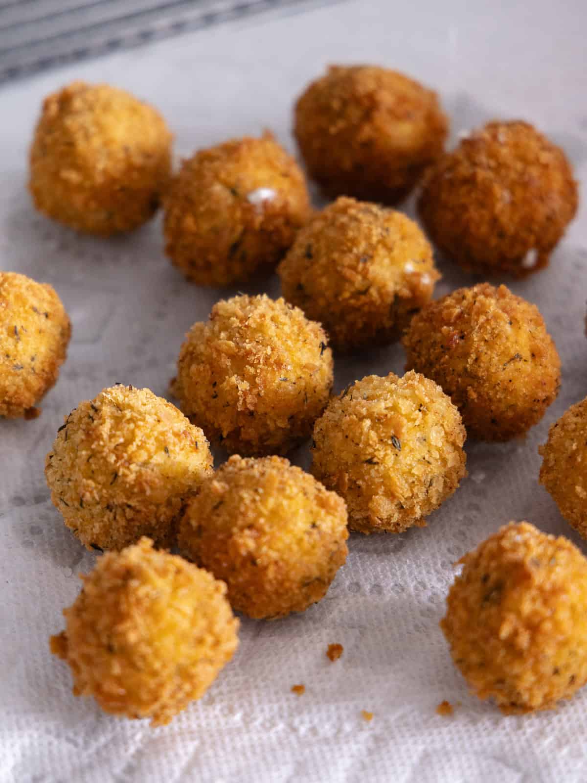 Fried goat cheese balls on a paper towel lined wire rack.