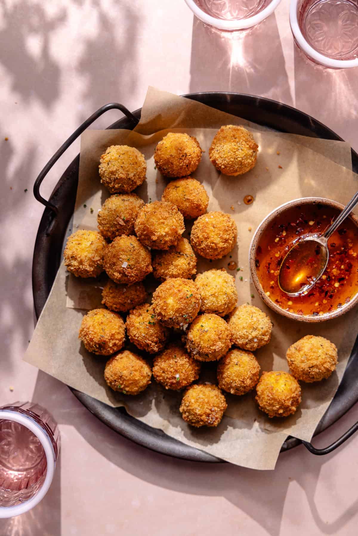 Fried goat cheese balls on a serving platter with a bowl of hot honey.