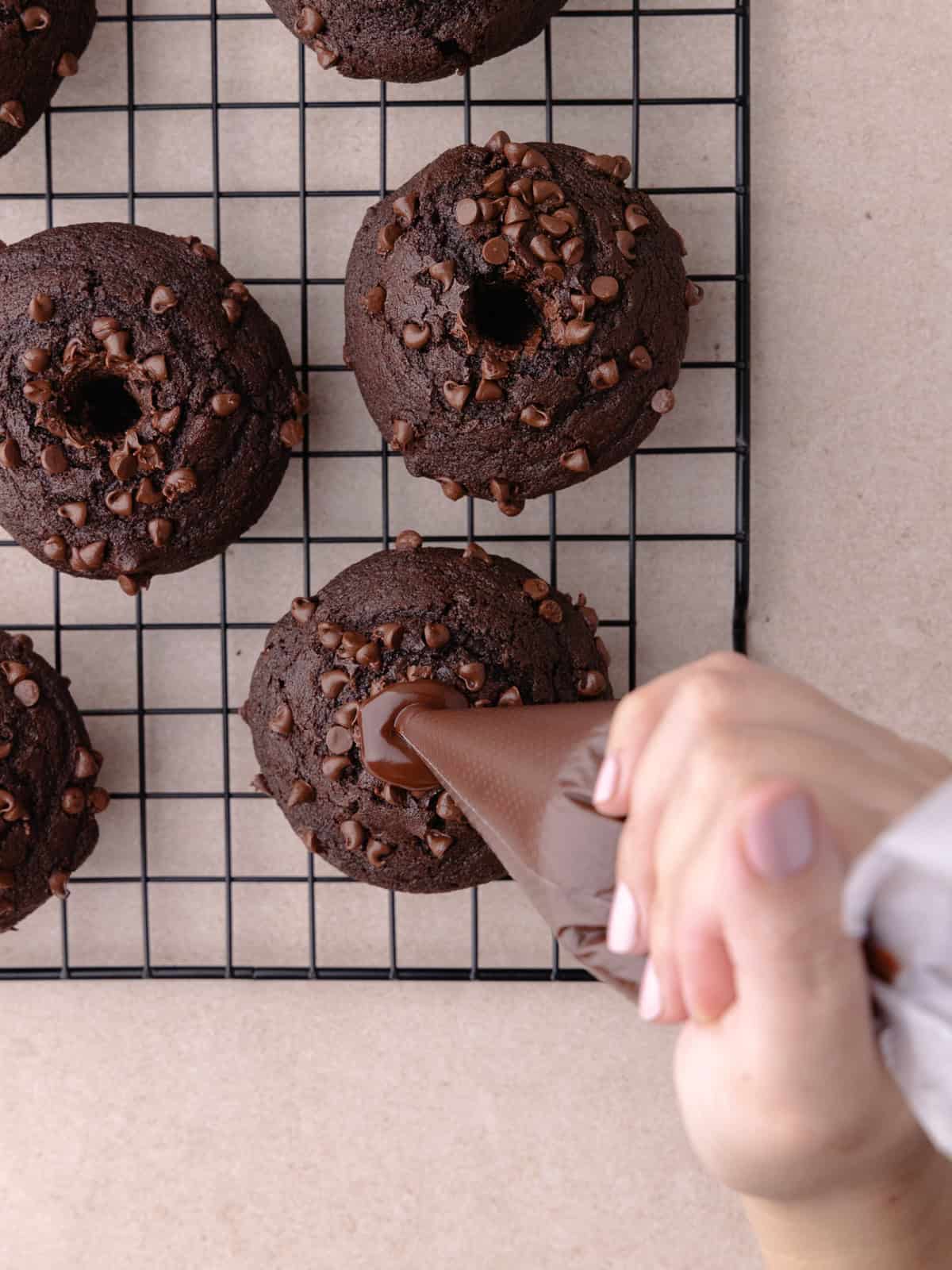 Chocolate ganache is piped into the center of each muffin.