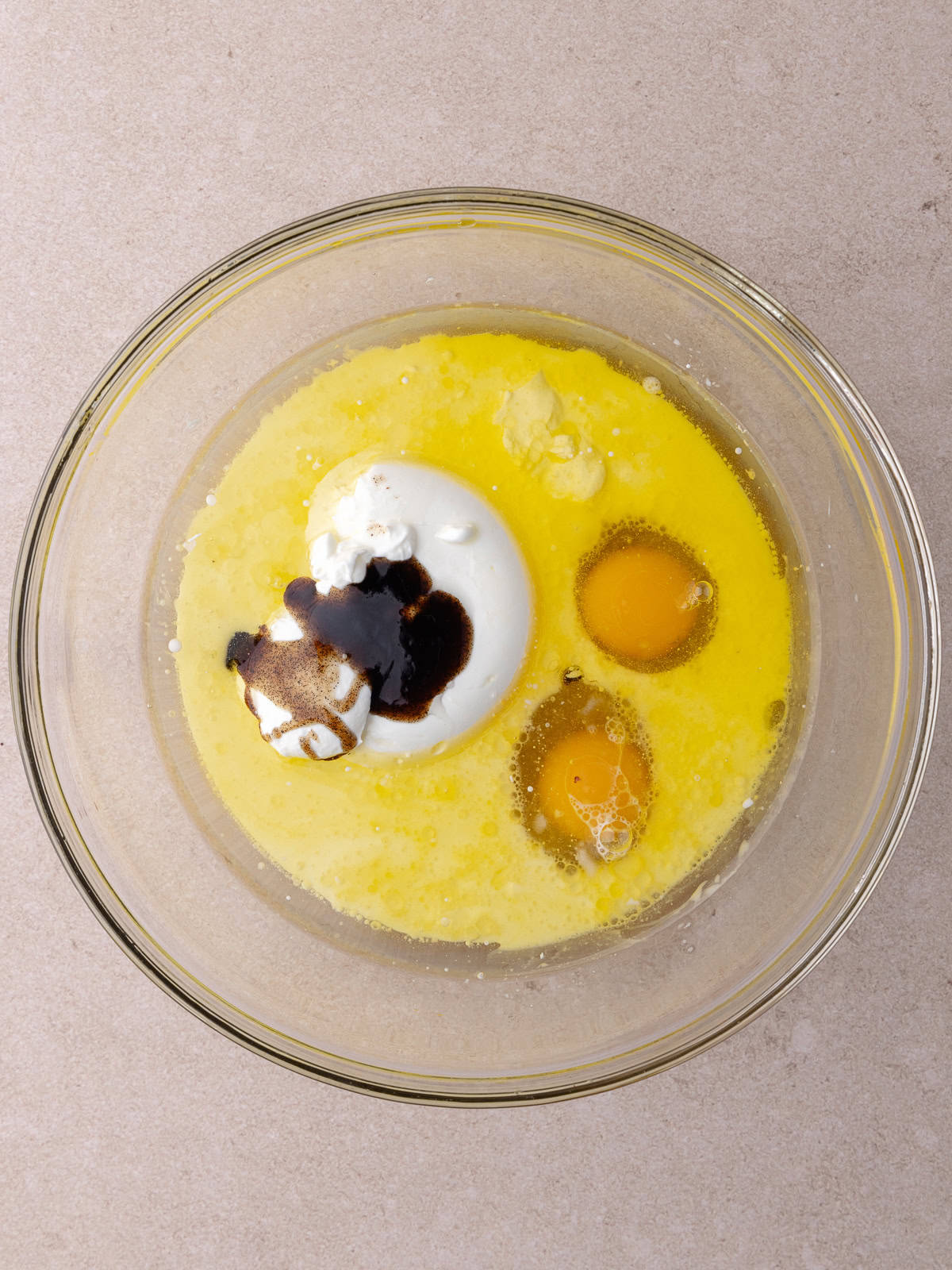 Oil, melted butter, milk, sour cream, eggs and vanilla are in a mixing bowl.